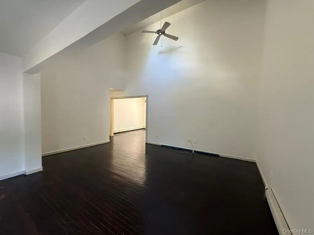 Bonus room featuring high vaulted ceiling, dark wood-style flooring, ceiling fan, and baseboard heating Bonus room featuring high vaulted ceiling, dark wood-style flooring, ceiling fan, and baseboard heating