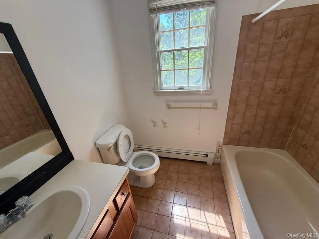 Full bath featuring baseboard heating, vanity, shower / bathtub combination, and light tile patterned floors Full bath featuring baseboard heating, vanity, shower / bathtub combination, and light tile patterned floors