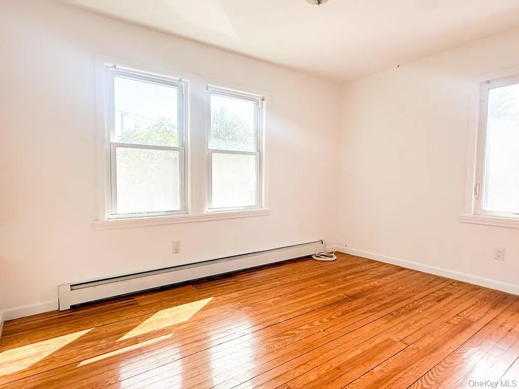 Spare room with a baseboard heating unit and light wood-style floors Spare room with a baseboard heating unit and light wood-style floors