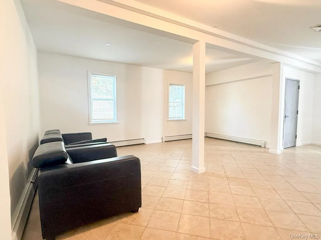 Living room featuring a baseboard heating unit, a baseboard radiator, and light tile patterned floors Living room featuring a baseboard heating unit, a baseboard radiator, and light tile patterned floors