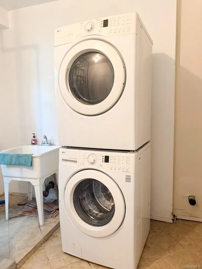Laundry room featuring stacked washing machine and dryer and light tile patterned floors Laundry room featuring stacked washing machine and dryer and light tile patterned floors