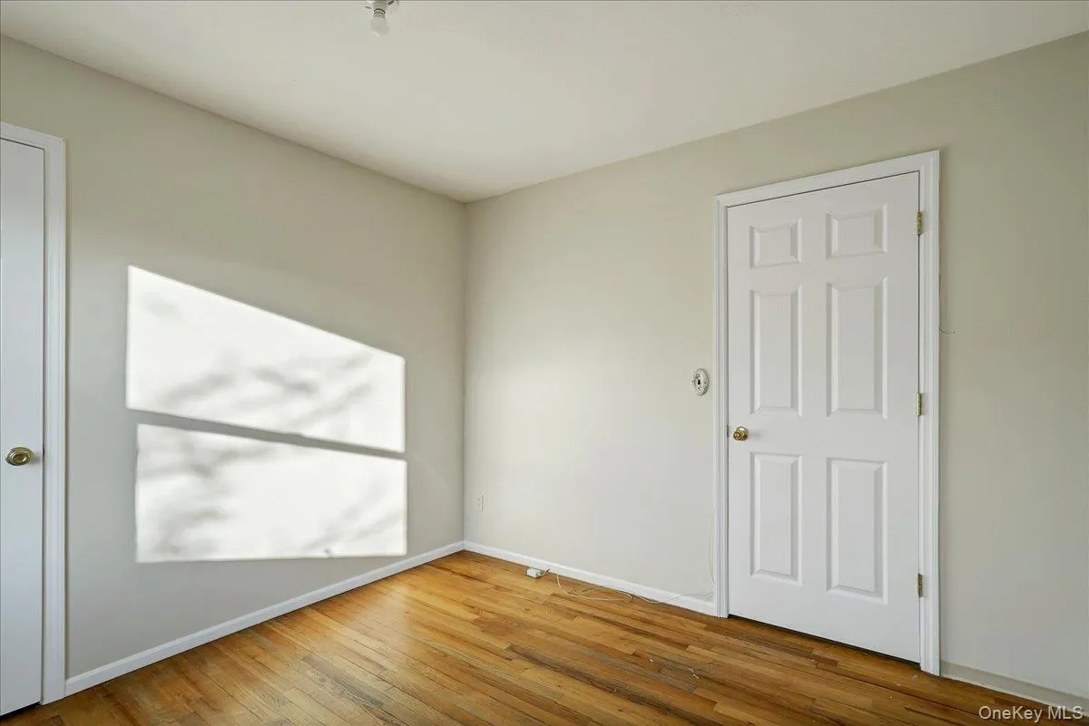 Unfurnished room with baseboards and hardwood / wood-style flooring Unfurnished room with baseboards and hardwood / wood-style flooring