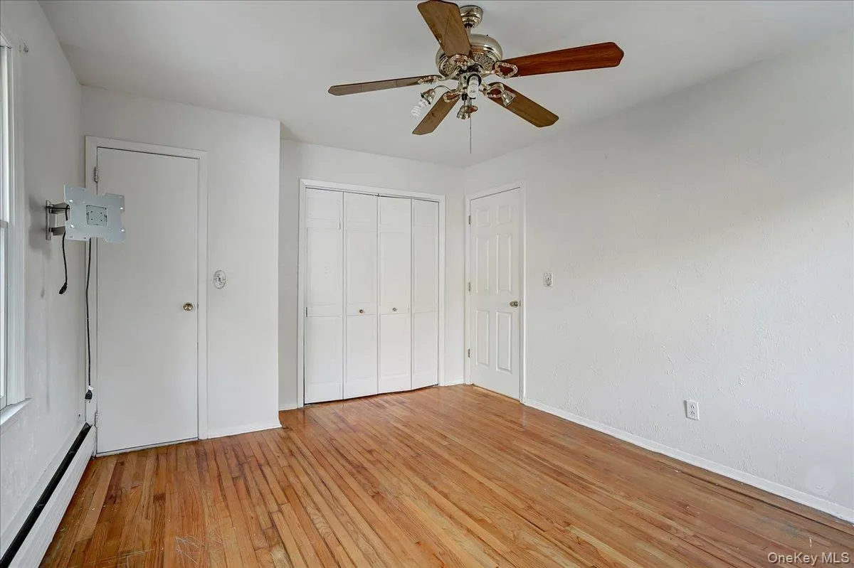 Unfurnished bedroom featuring a baseboard heating unit, light wood-type flooring, a ceiling fan, and a closet Unfurnished bedroom featuring a baseboard heating unit, light wood-type flooring, a ceiling fan, and a closet