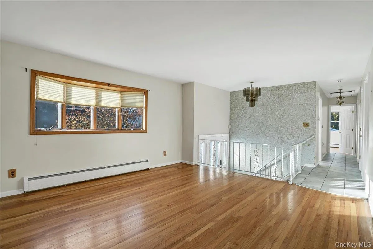Unfurnished room with healthy amount of natural light, a baseboard radiator, and light wood-type flooring Unfurnished room with healthy amount of natural light, a baseboard radiator, and light wood-type flooring