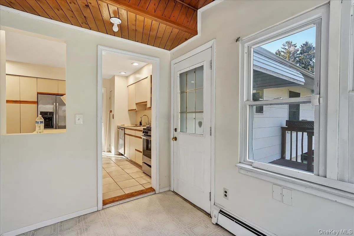 Doorway to outside featuring a baseboard radiator, wooden ceiling, and tile patterned floors Doorway to outside featuring a baseboard radiator, wooden ceiling, and tile patterned floors