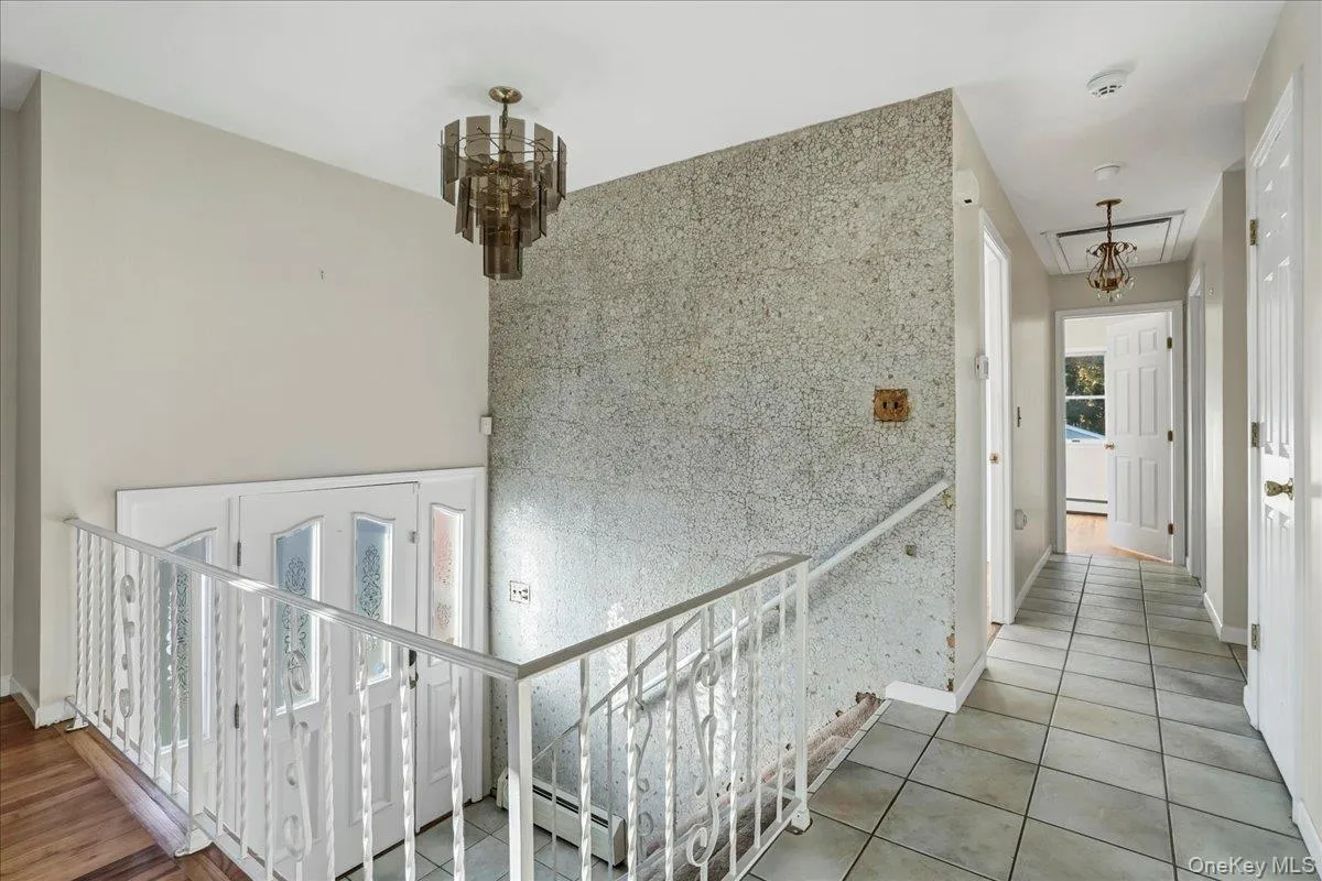 Hallway featuring tile patterned flooring and baseboard heating Hallway featuring tile patterned flooring and baseboard heating