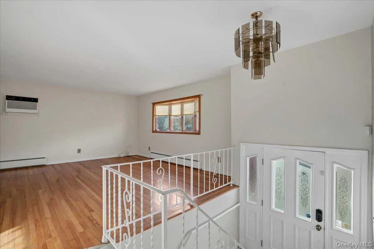 Entrance foyer featuring light wood-type flooring, an AC wall unit, and a baseboard heating unit Entrance foyer featuring light wood-type flooring, an AC wall unit, and a baseboard heating unit