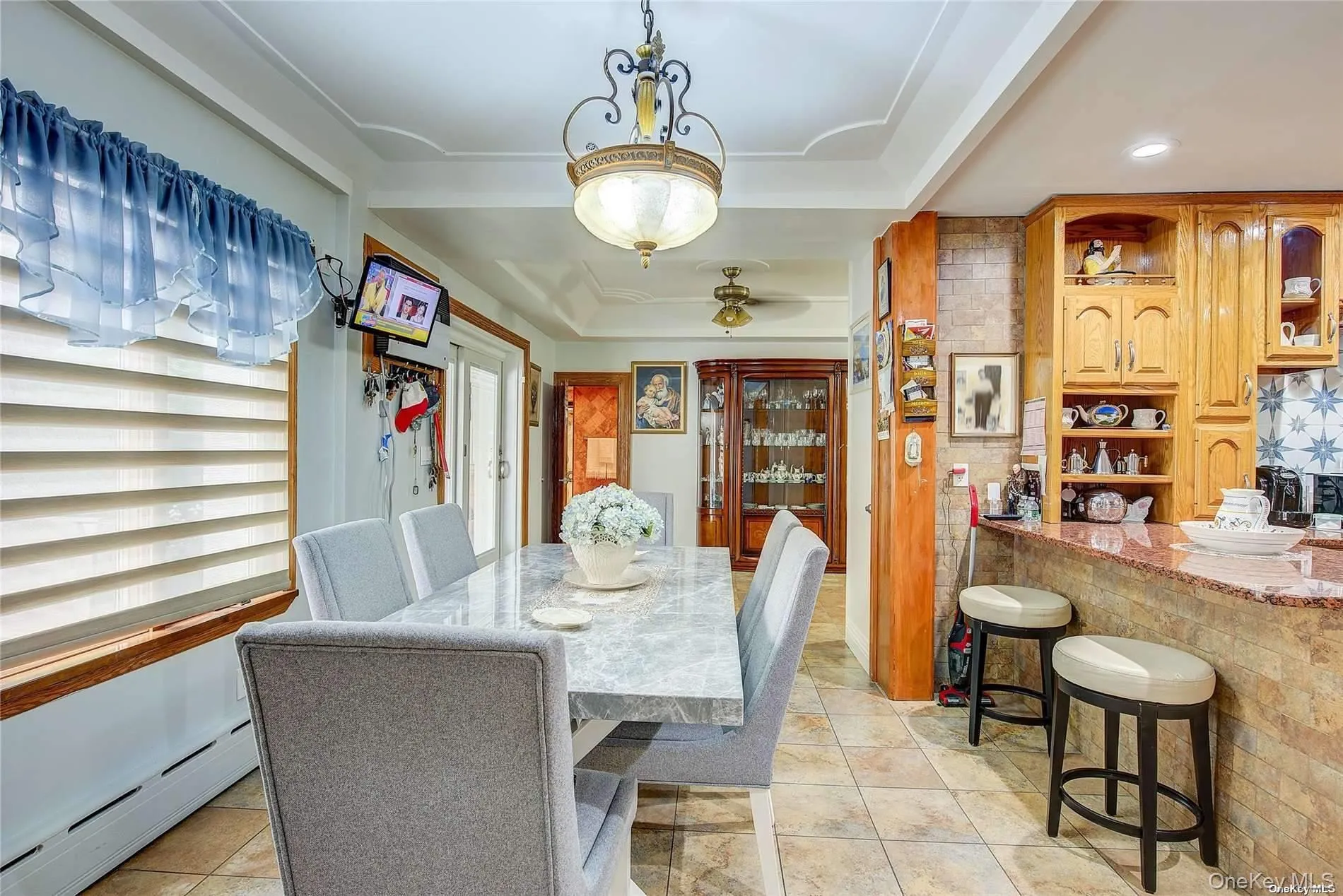 Dining room featuring a baseboard heating unit, light tile patterned floors, and a tray ceiling Dining room featuring a baseboard heating unit, light tile patterned floors, and a tray ceiling