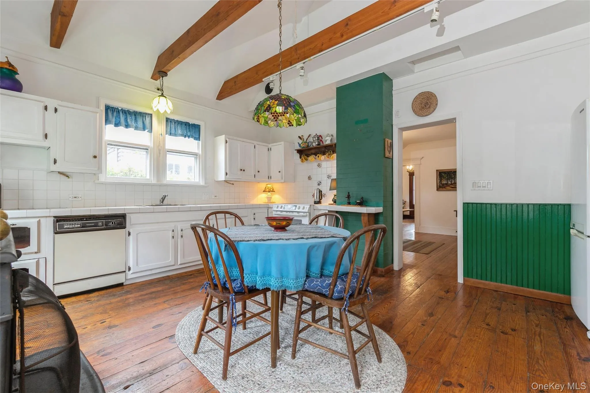 Dining space featuring dark wood finished floors, beam ceiling, and wainscoting Dining space featuring dark wood finished floors, beam ceiling, and wainscoting