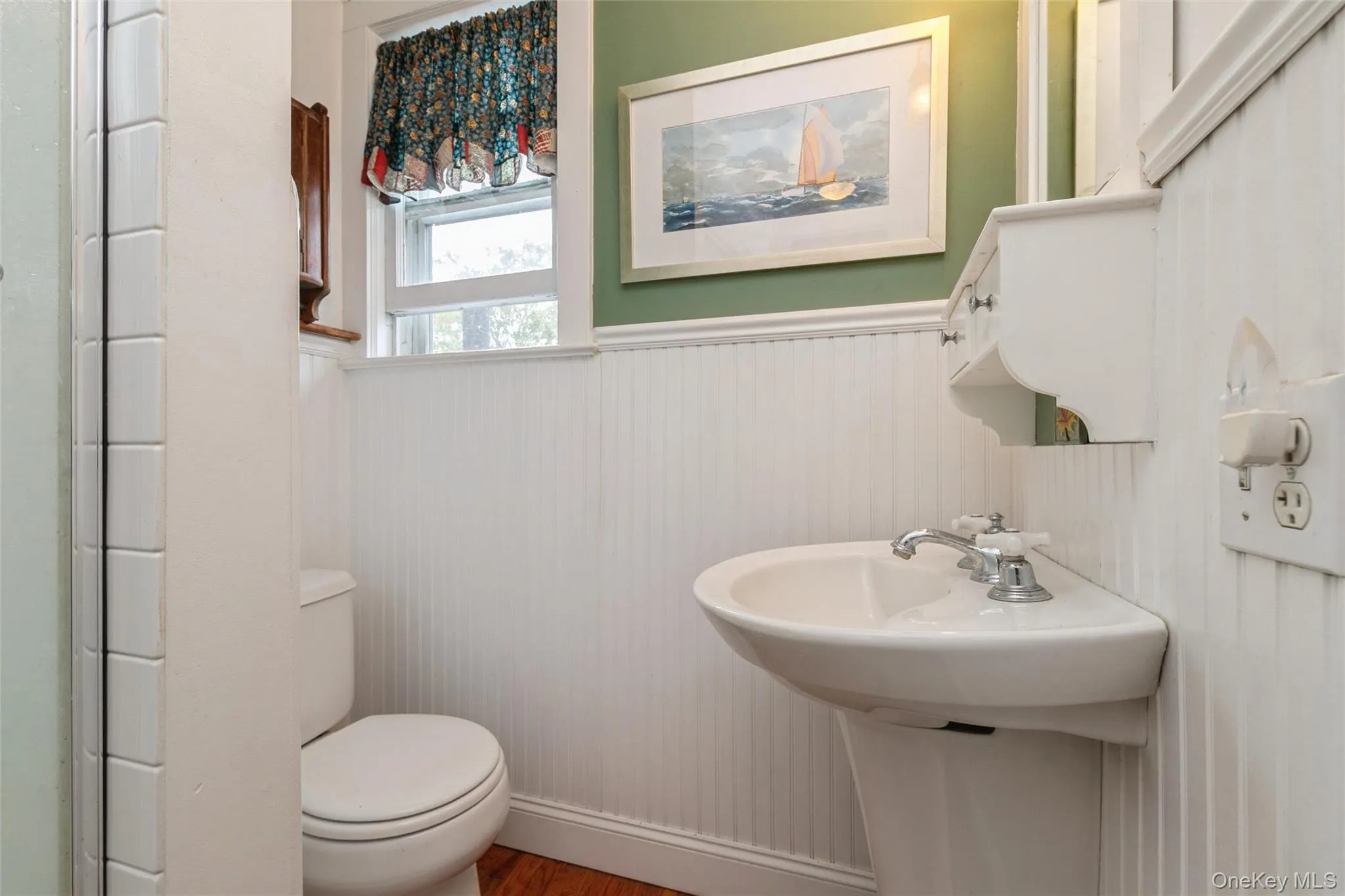 Bathroom featuring wainscoting and wood finished floors Bathroom featuring wainscoting and wood finished floors