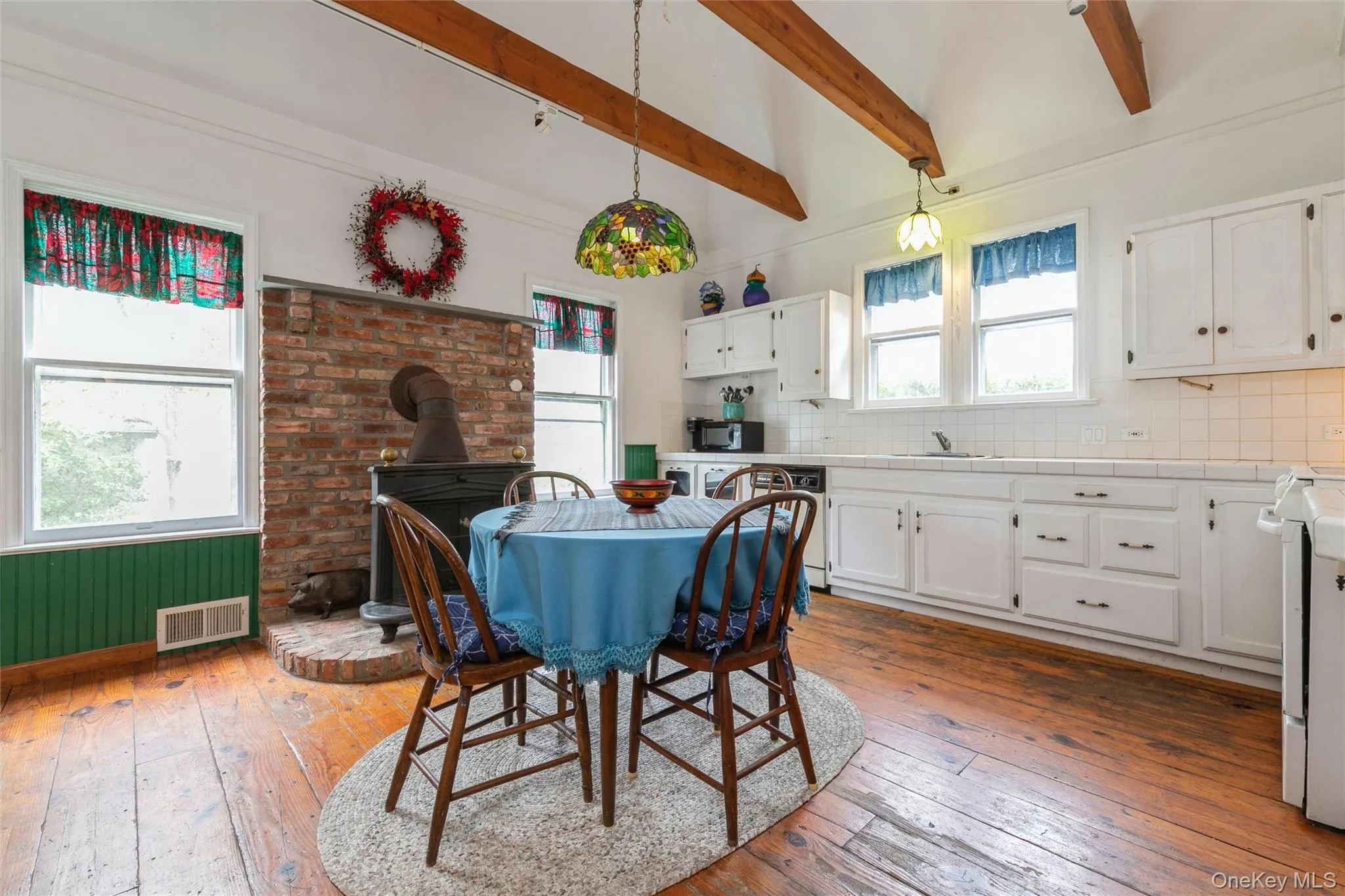 Dining room with light wood finished floors, beamed ceiling, and a wood stove Dining room with light wood finished floors, beamed ceiling, and a wood stove