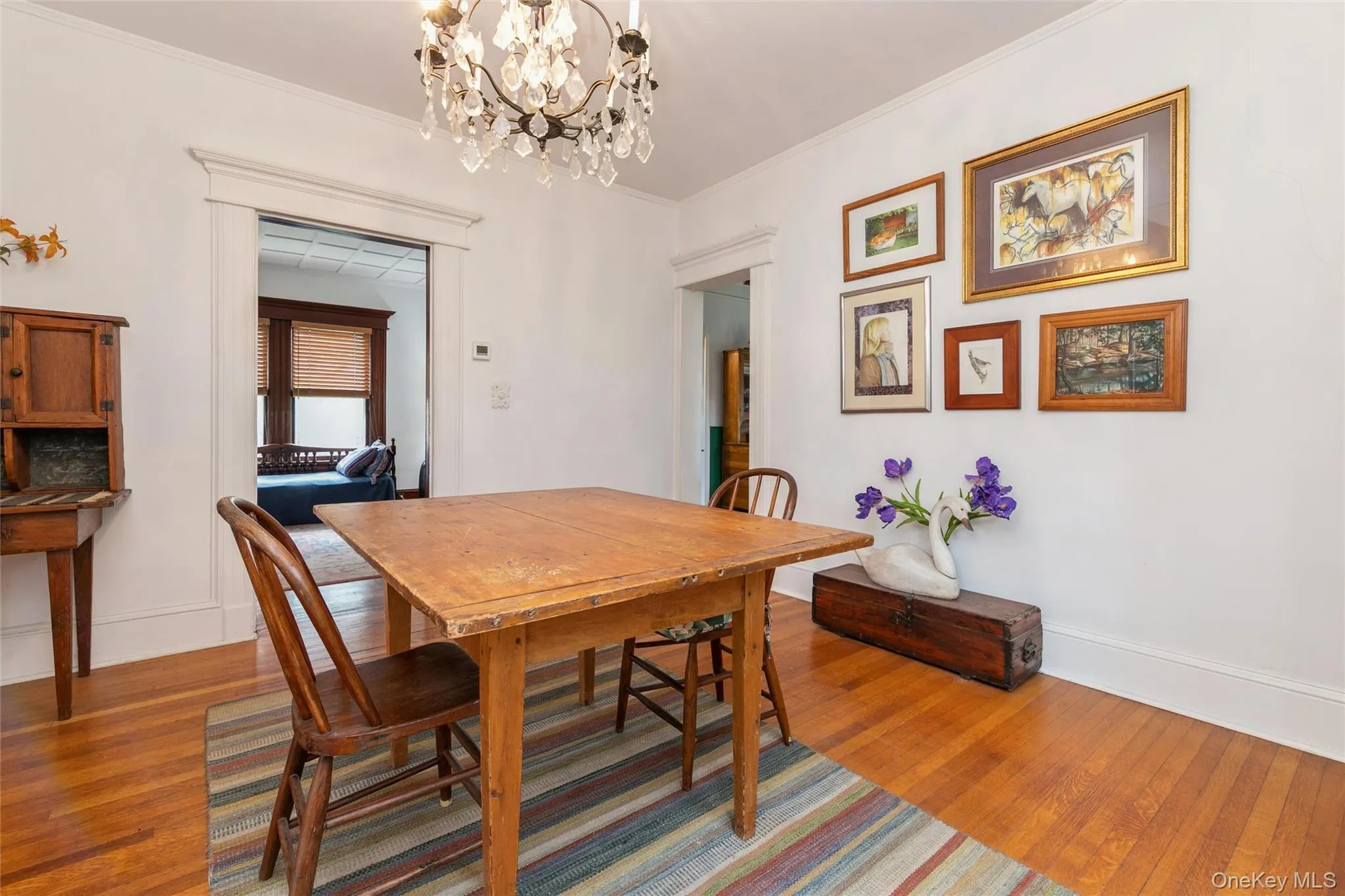 Dining room featuring wood finished floors, a chandelier, and ornamental molding Dining room featuring wood finished floors, a chandelier, and ornamental molding