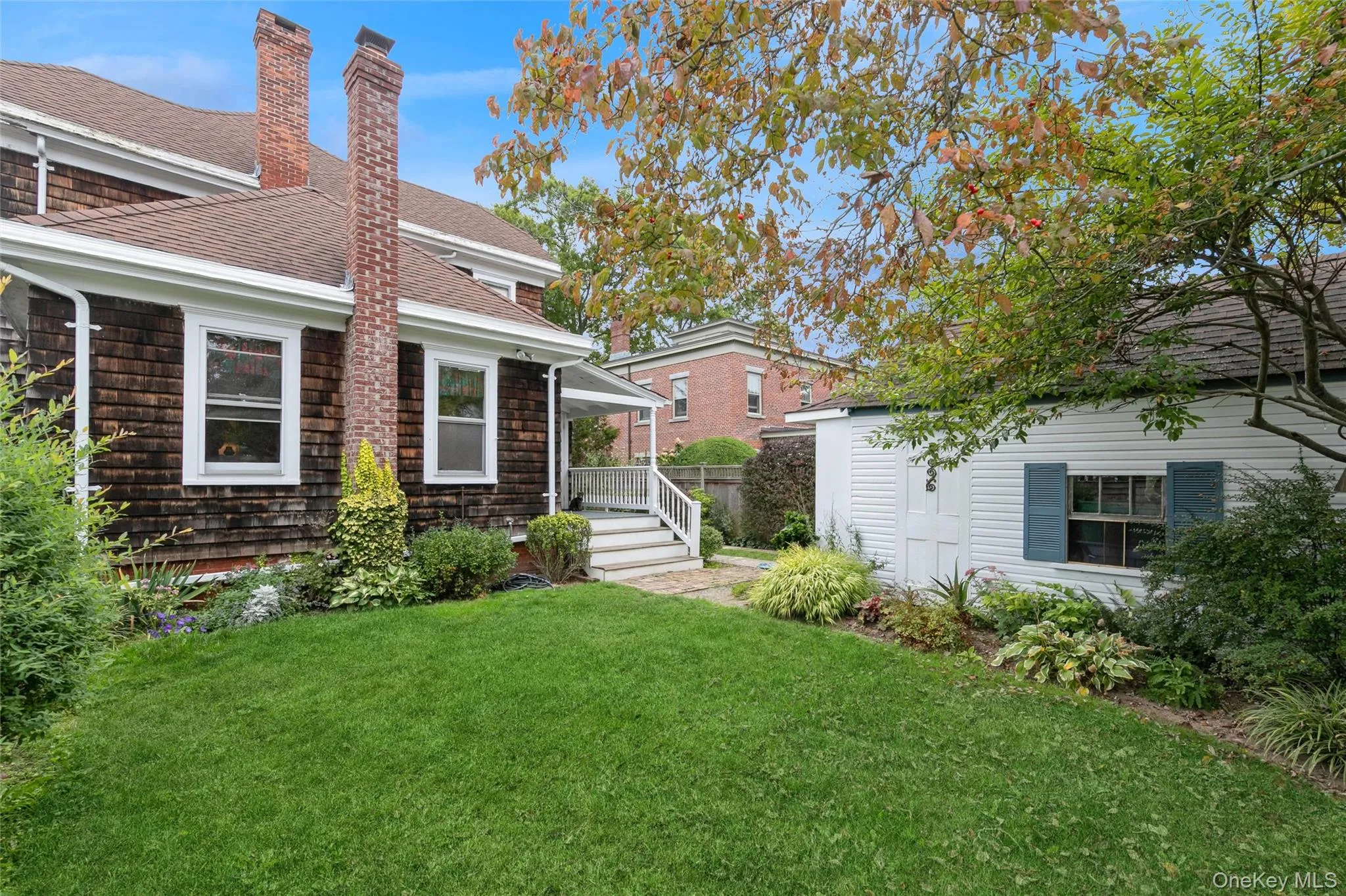 Back of house featuring a chimney, a yard, a shingled roof, and an outbuilding Back of house featuring a chimney, a yard, a shingled roof, and an outbuilding