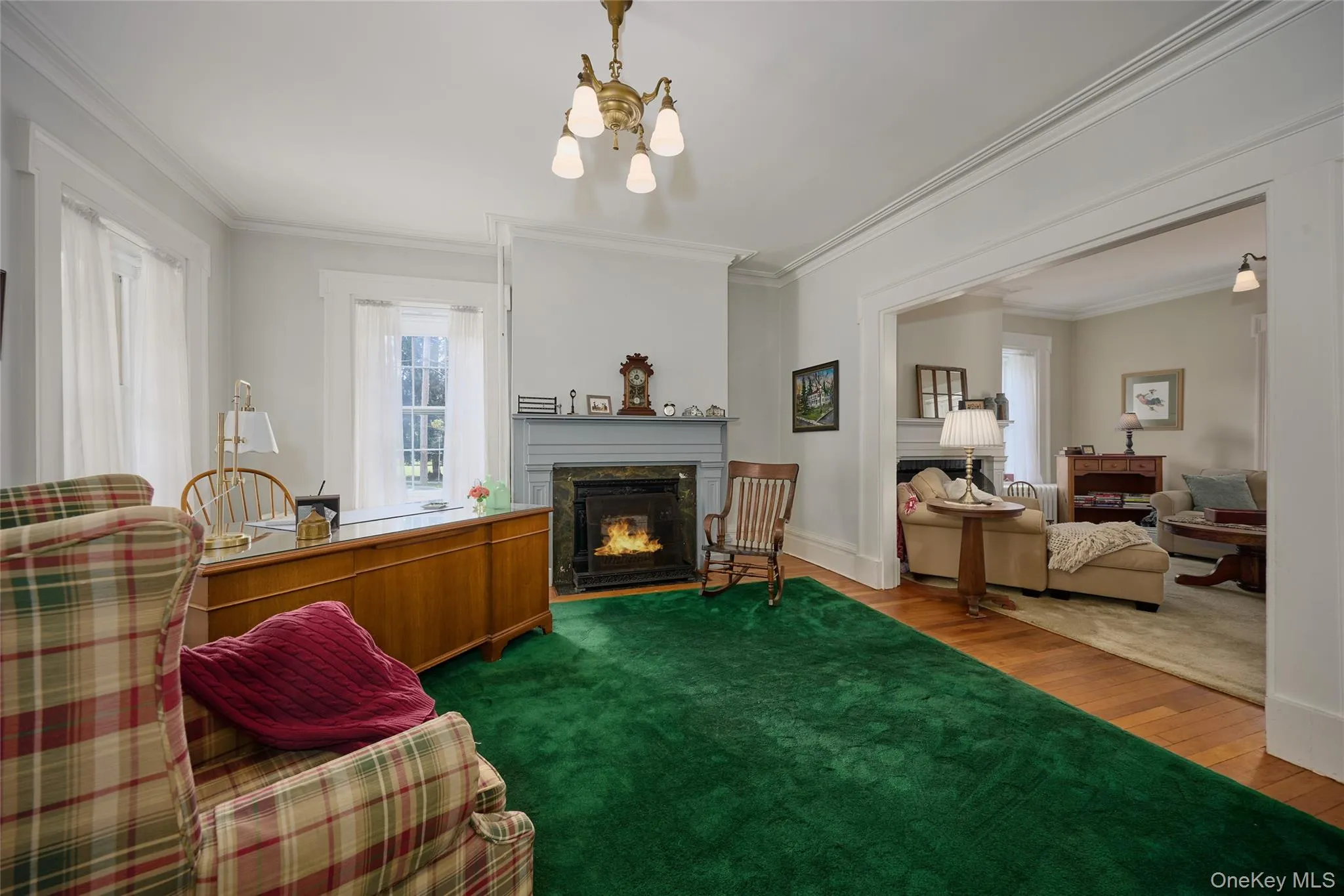 Living area with a lit fireplace, crown molding, wood finished floors, and a chandelier Living area with a lit fireplace, crown molding, wood finished floors, and a chandelier