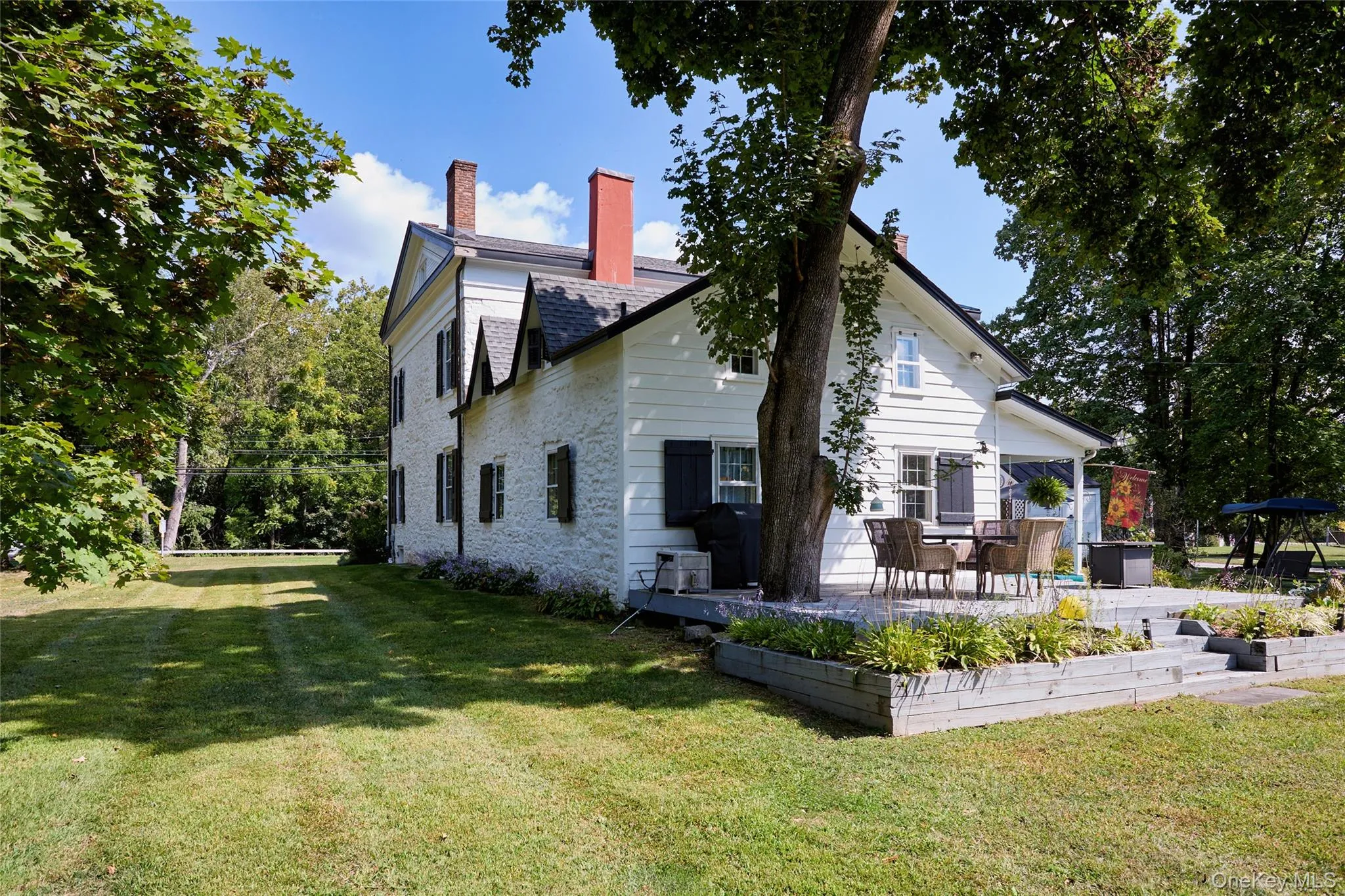 Back of property featuring a lawn, a patio, and a chimney Back of property featuring a lawn, a patio, and a chimney
