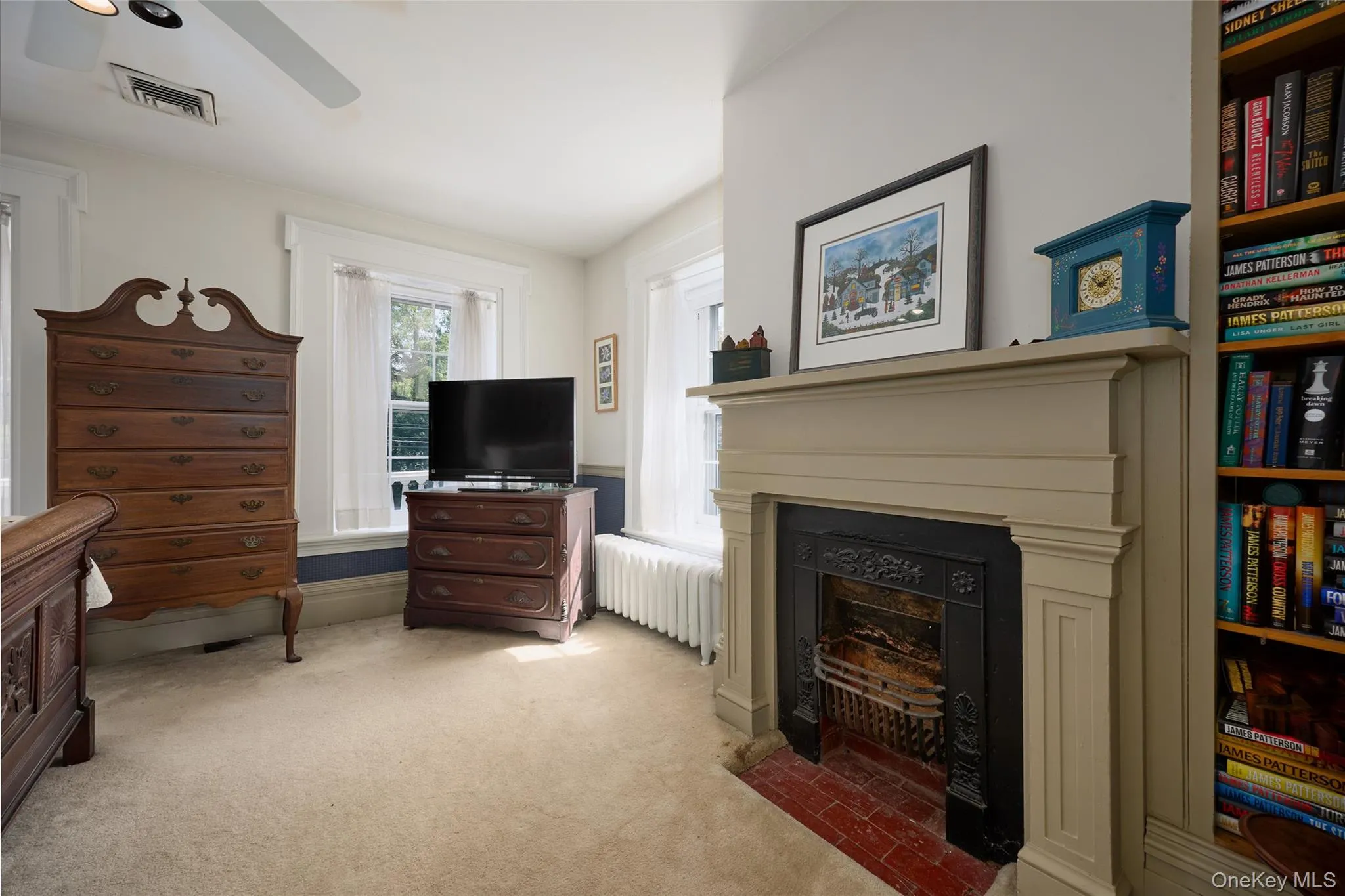 Living room with radiator, light carpet, a fireplace with flush hearth, and ceiling fan Living room with radiator, light carpet, a fireplace with flush hearth, and ceiling fan