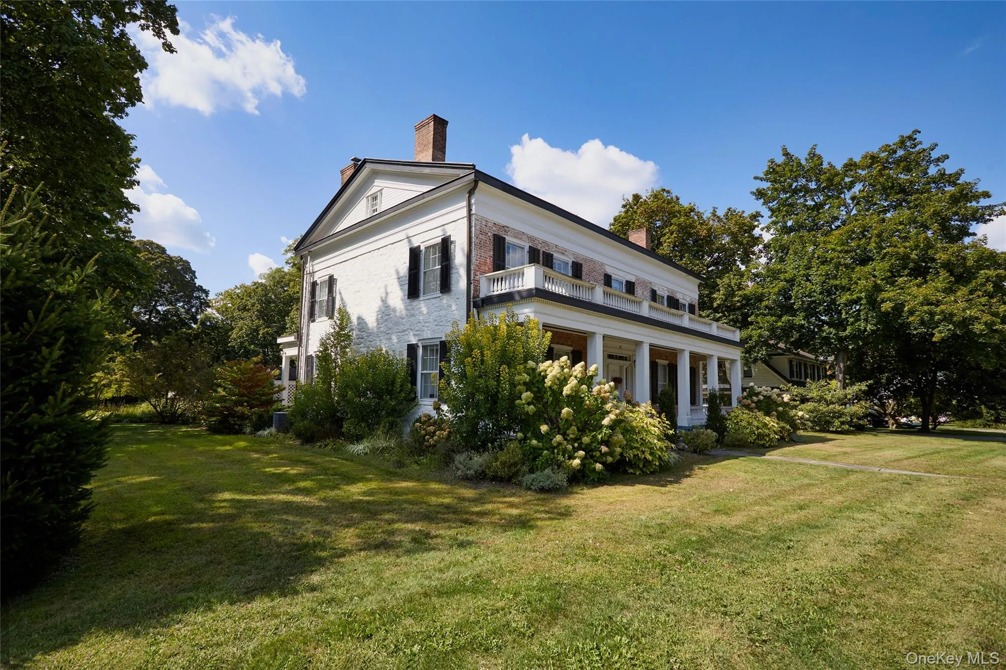 View of home's exterior featuring a chimney, a lawn, covered porch, and brick siding View of home's exterior featuring a chimney, a lawn, covered porch, and brick siding