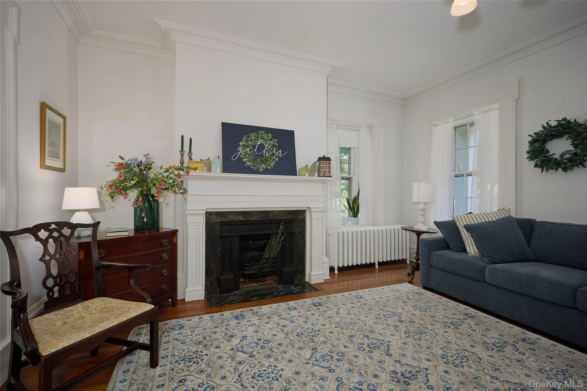 Living area with radiator heating unit, wood finished floors, ornamental molding, and a high end fireplace Living area with radiator heating unit, wood finished floors, ornamental molding, and a high end fireplace