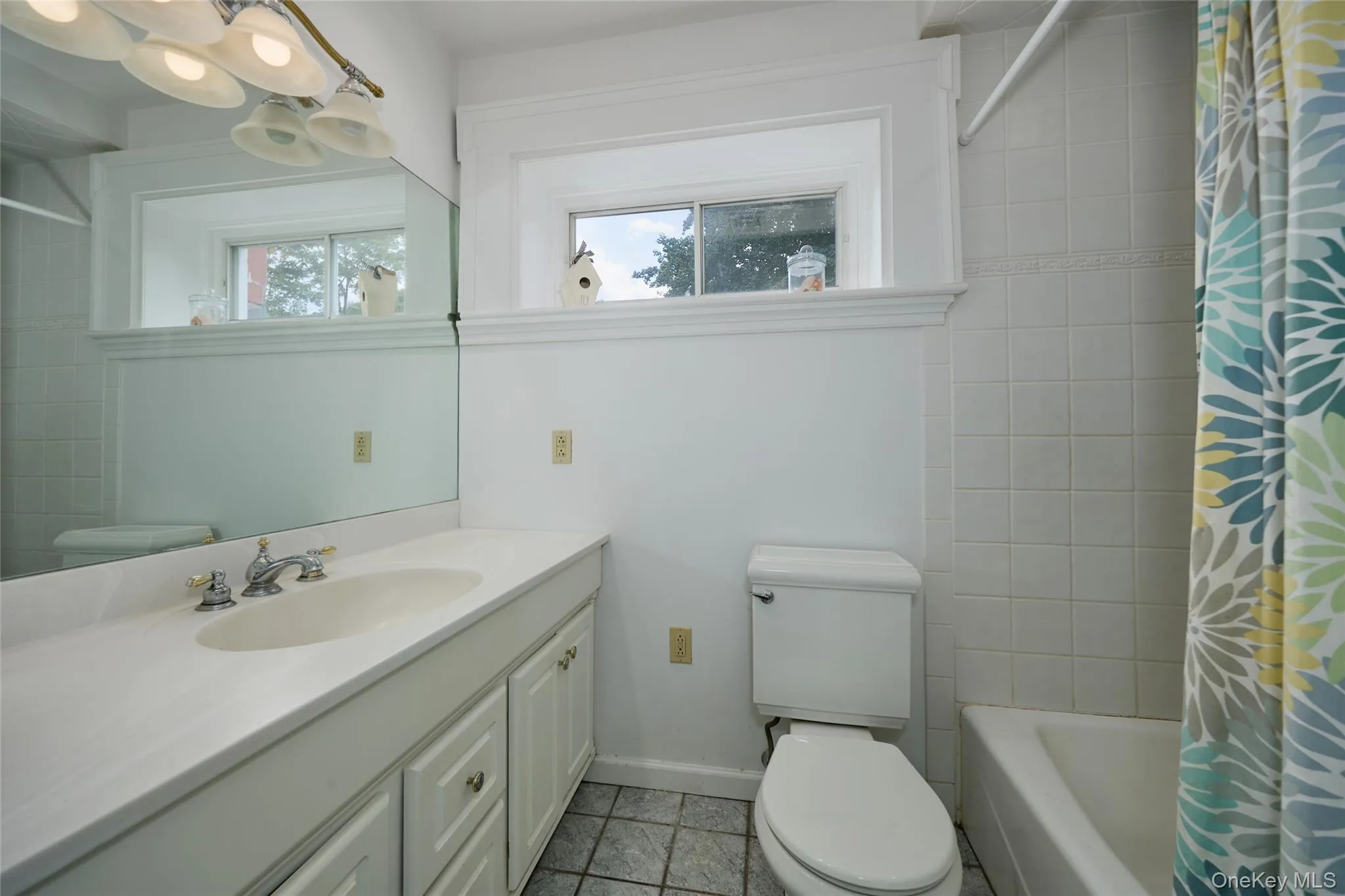 Full bath with plenty of natural light, vanity, shower / tub combo with curtain, and light tile patterned flooring Full bath with plenty of natural light, vanity, shower / tub combo with curtain, and light tile patterned flooring
