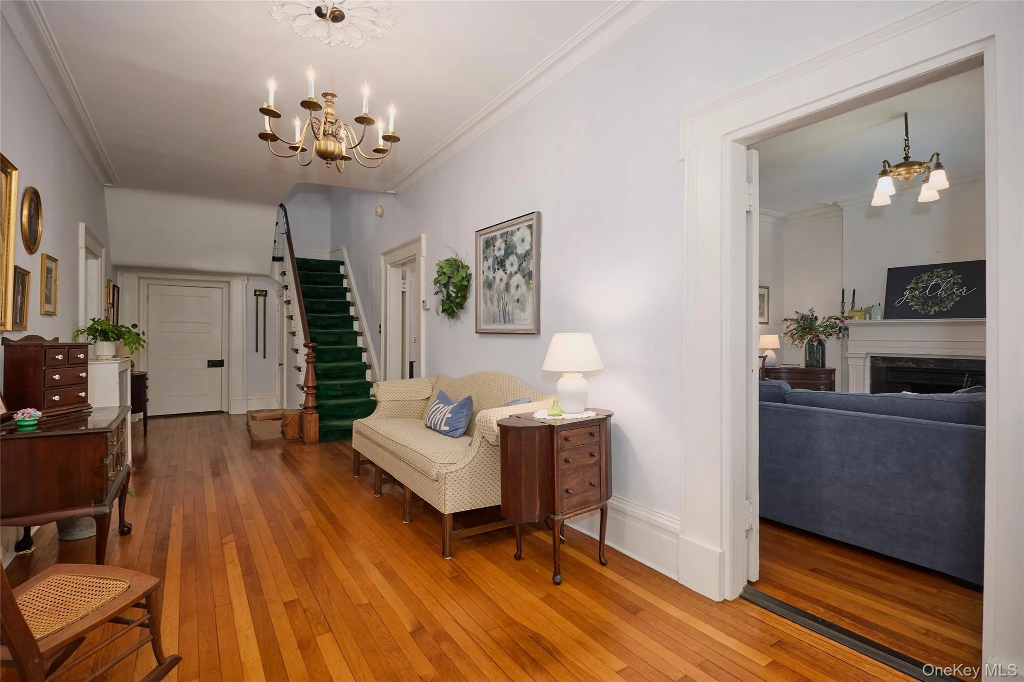Sitting room featuring a chandelier, crown molding, wood-type flooring, a fireplace, and stairs Sitting room featuring a chandelier, crown molding, wood-type flooring, a fireplace, and stairs