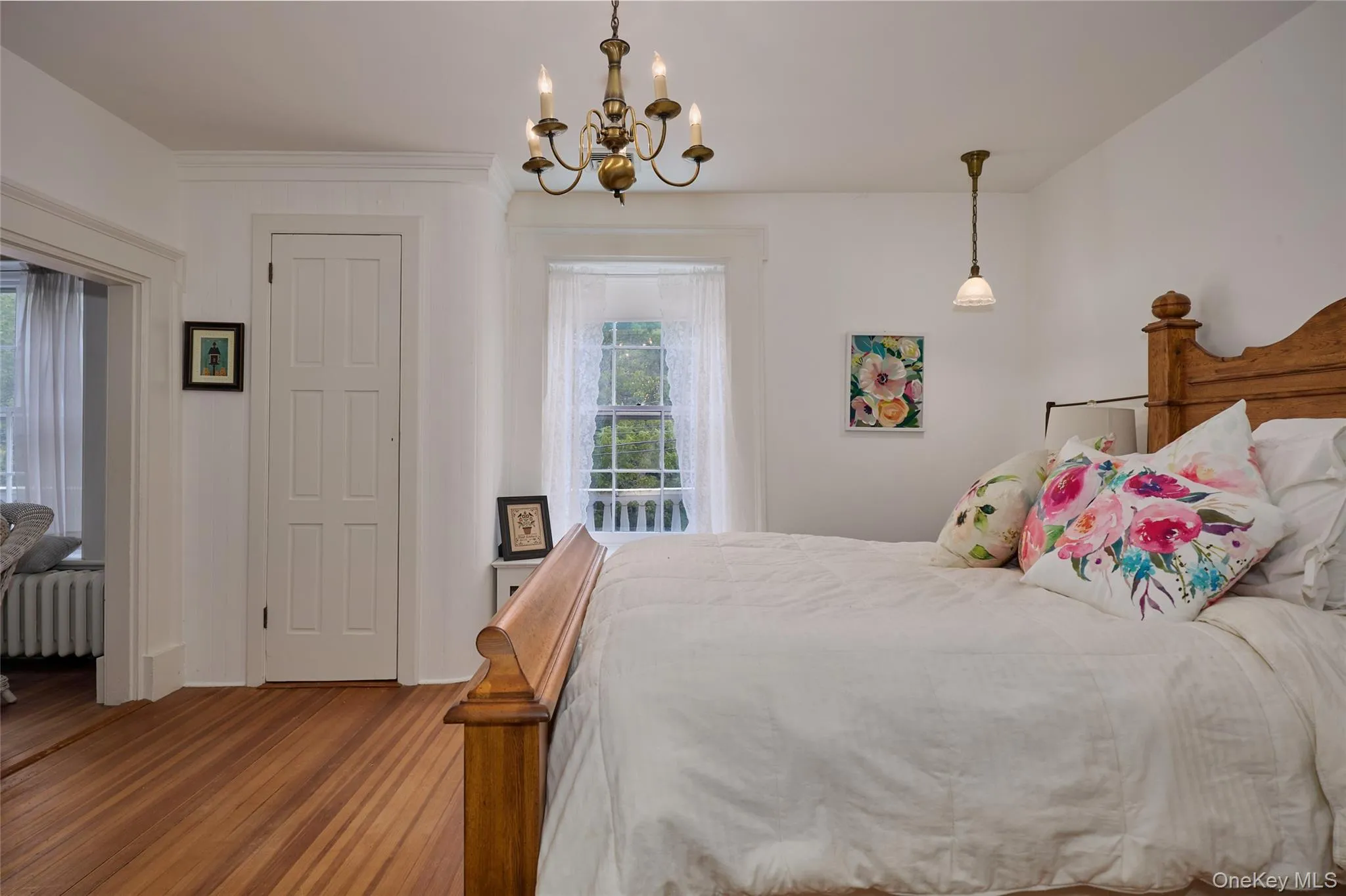 Bedroom featuring radiator, a chandelier, and wood finished floors Bedroom featuring radiator, a chandelier, and wood finished floors