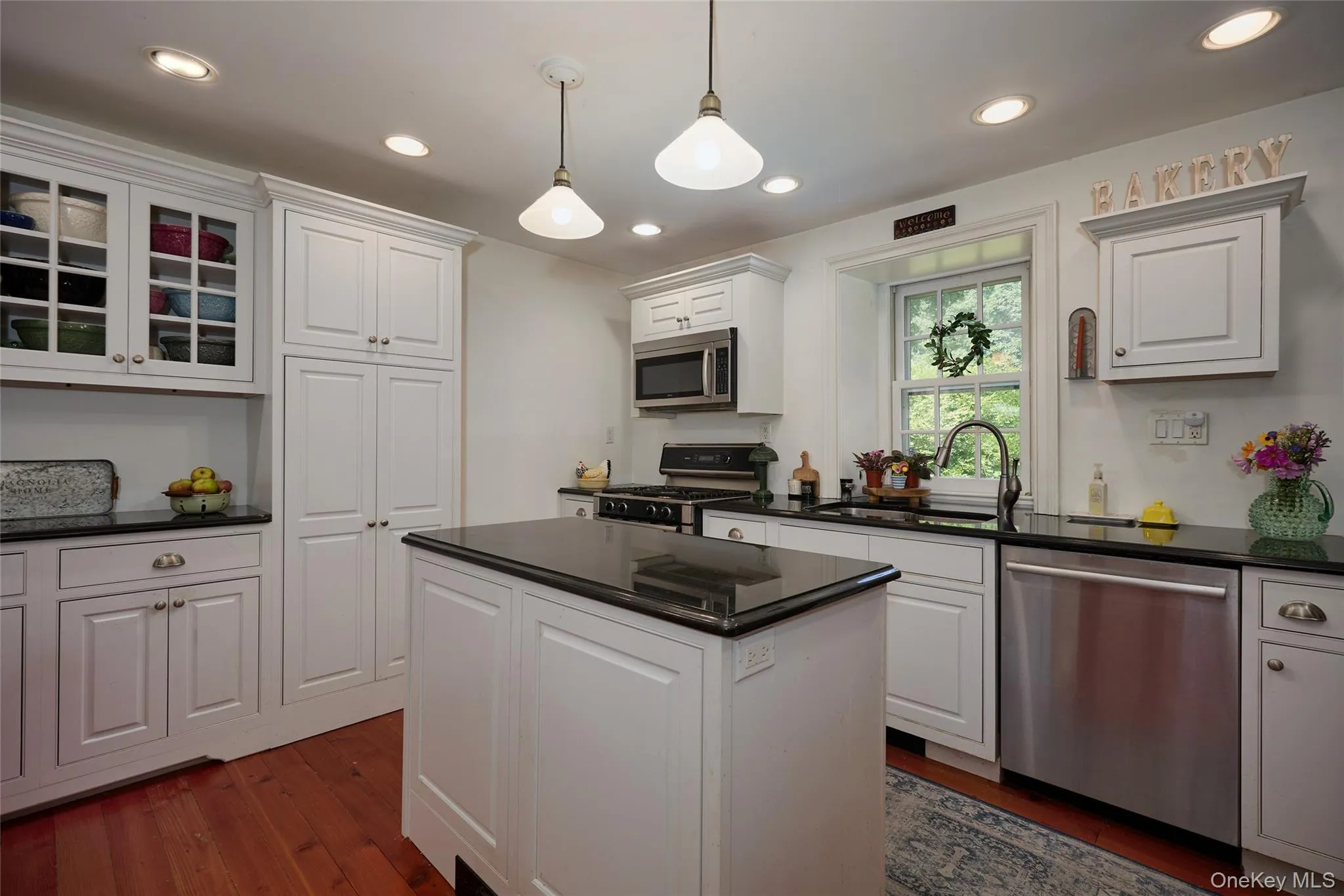 Kitchen featuring stainless steel appliances, hanging light fixtures, dark wood finished floors, recessed lighting, and glass insert cabinets Kitchen featuring stainless steel appliances, hanging light fixtures, dark wood finished floors, recessed lighting, and glass insert cabinets