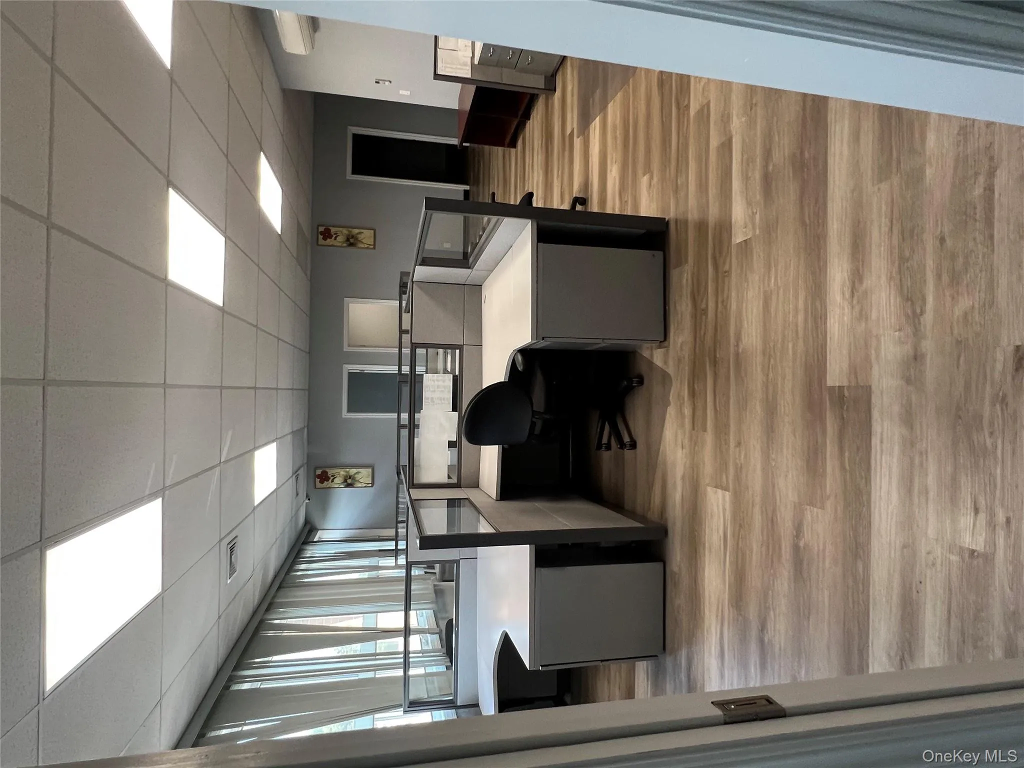 Office area with a drop ceiling, light wood-style floors, and a wall unit AC Office area with a drop ceiling, light wood-style floors, and a wall unit AC