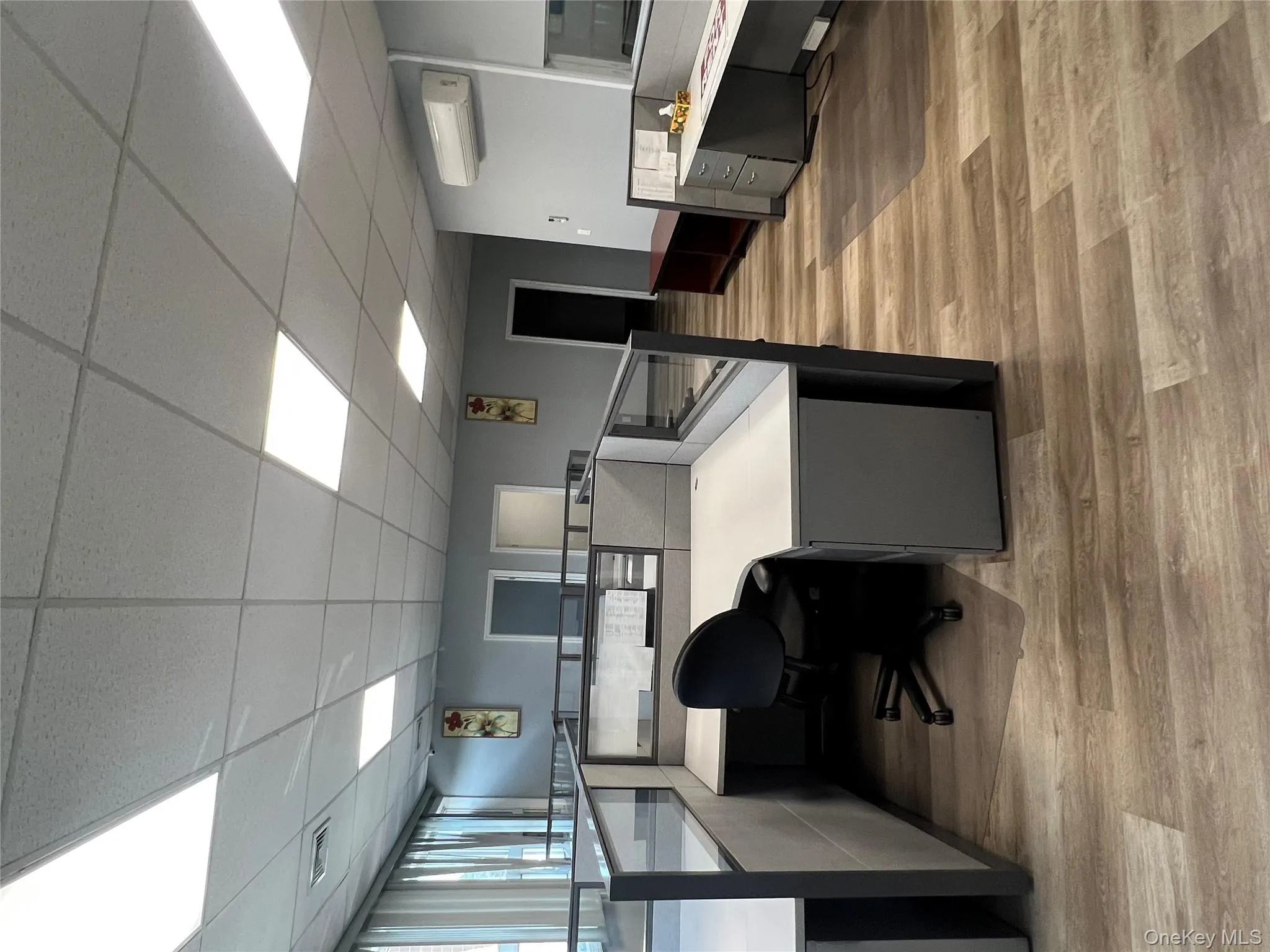 Home office with a drop ceiling, light wood-type flooring, built in desk, and a wall mounted AC Home office with a drop ceiling, light wood-type flooring, built in desk, and a wall mounted AC