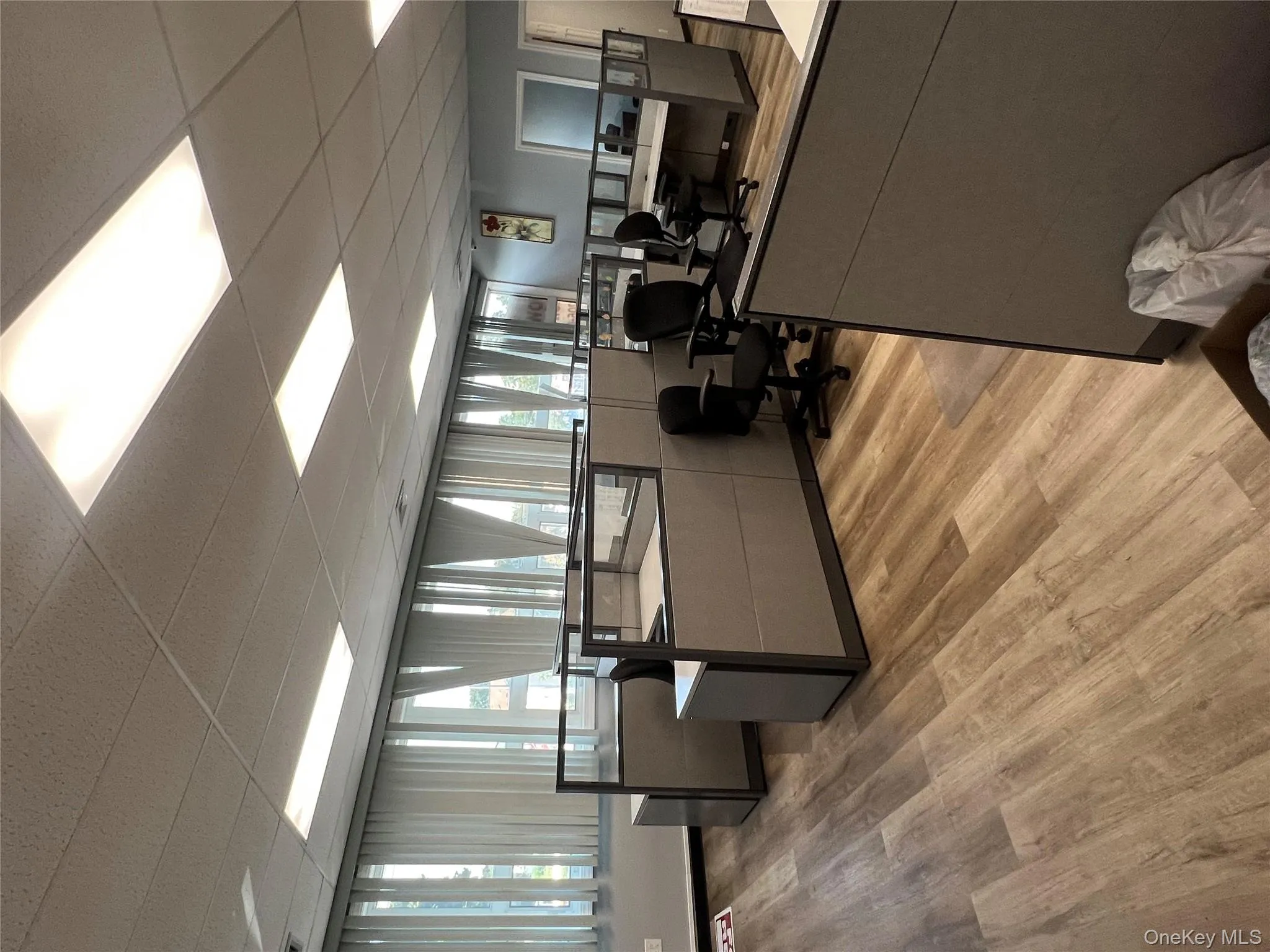 Office area featuring a paneled ceiling, light wood-style floors, and plenty of natural light Office area featuring a paneled ceiling, light wood-style floors, and plenty of natural light