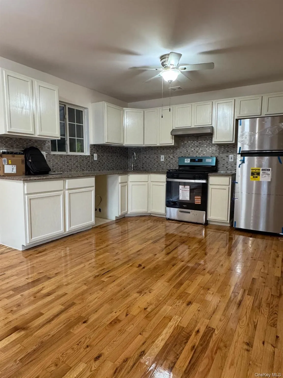 Kitchen featuring tasteful backsplash, appliances with stainless steel finishes, light wood-type flooring, and ceiling fan Kitchen featuring tasteful backsplash, appliances with stainless steel finishes, light wood-type flooring, and ceiling fan