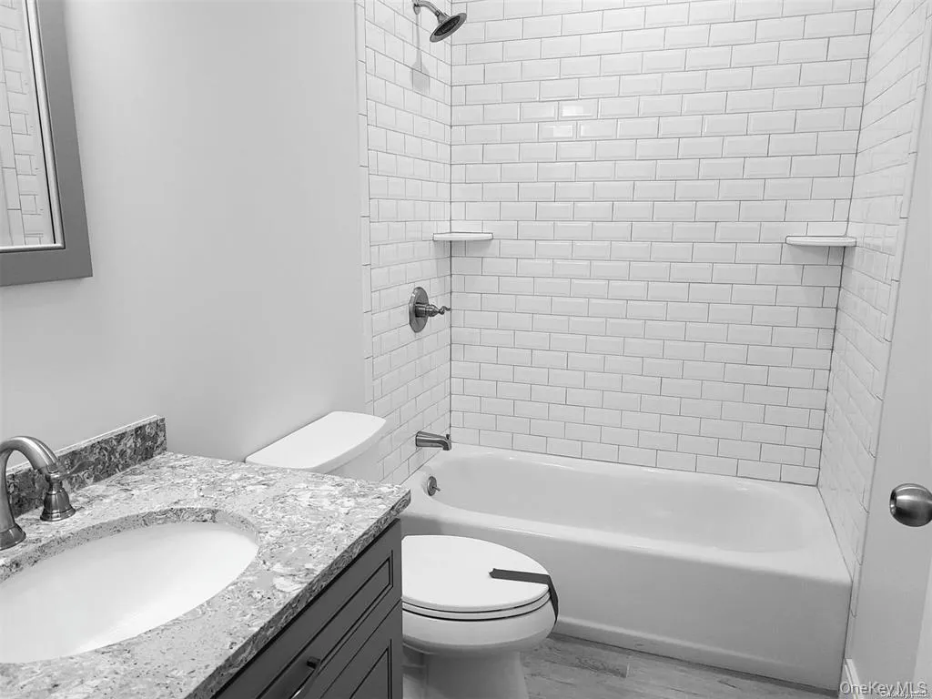 Full bath featuring bathing tub / shower combination, vanity, and light wood finished floors Full bath featuring bathing tub / shower combination, vanity, and light wood finished floors