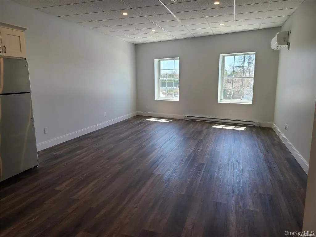 Spare room featuring a drop ceiling, dark wood-style floors, a baseboard radiator, recessed lighting, and a wall mounted AC Spare room featuring a drop ceiling, dark wood-style floors, a baseboard radiator, recessed lighting, and a wall mounted AC