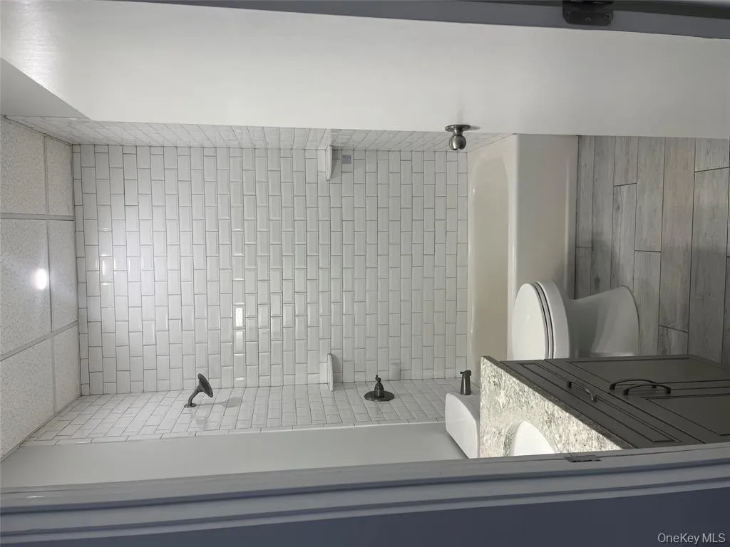 Full bath with a combined bath / shower with rainfall shower, vanity, light wood finished floors, and a drop ceiling Full bath with a combined bath / shower with rainfall shower, vanity, light wood finished floors, and a drop ceiling