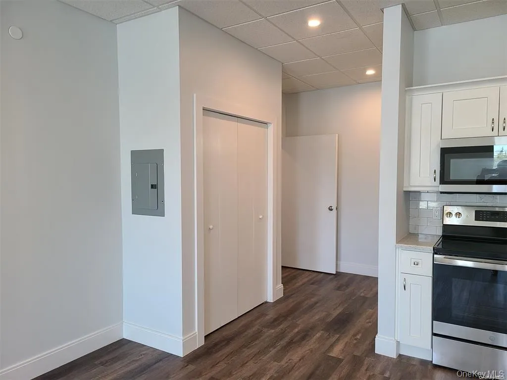 Kitchen with appliances with stainless steel finishes, white cabinets, a paneled ceiling, recessed lighting, and dark wood-type flooring Kitchen with appliances with stainless steel finishes, white cabinets, a paneled ceiling, recessed lighting, and dark wood-type flooring