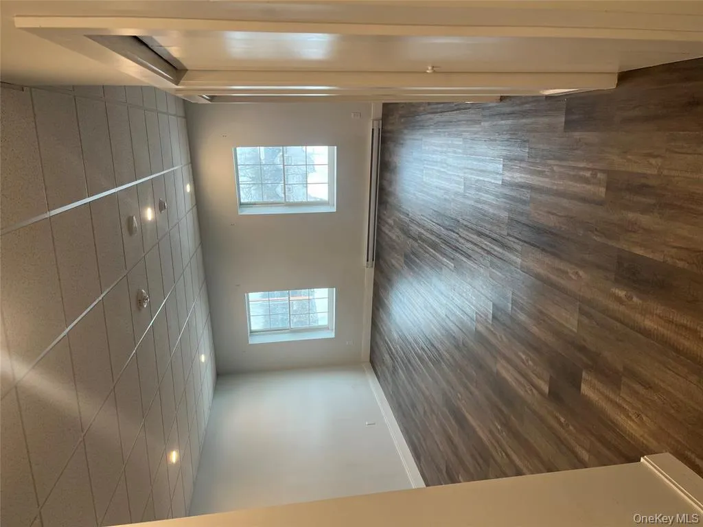 Empty room featuring a drop ceiling, dark wood-style flooring, a baseboard radiator, and recessed lighting Empty room featuring a drop ceiling, dark wood-style flooring, a baseboard radiator, and recessed lighting
