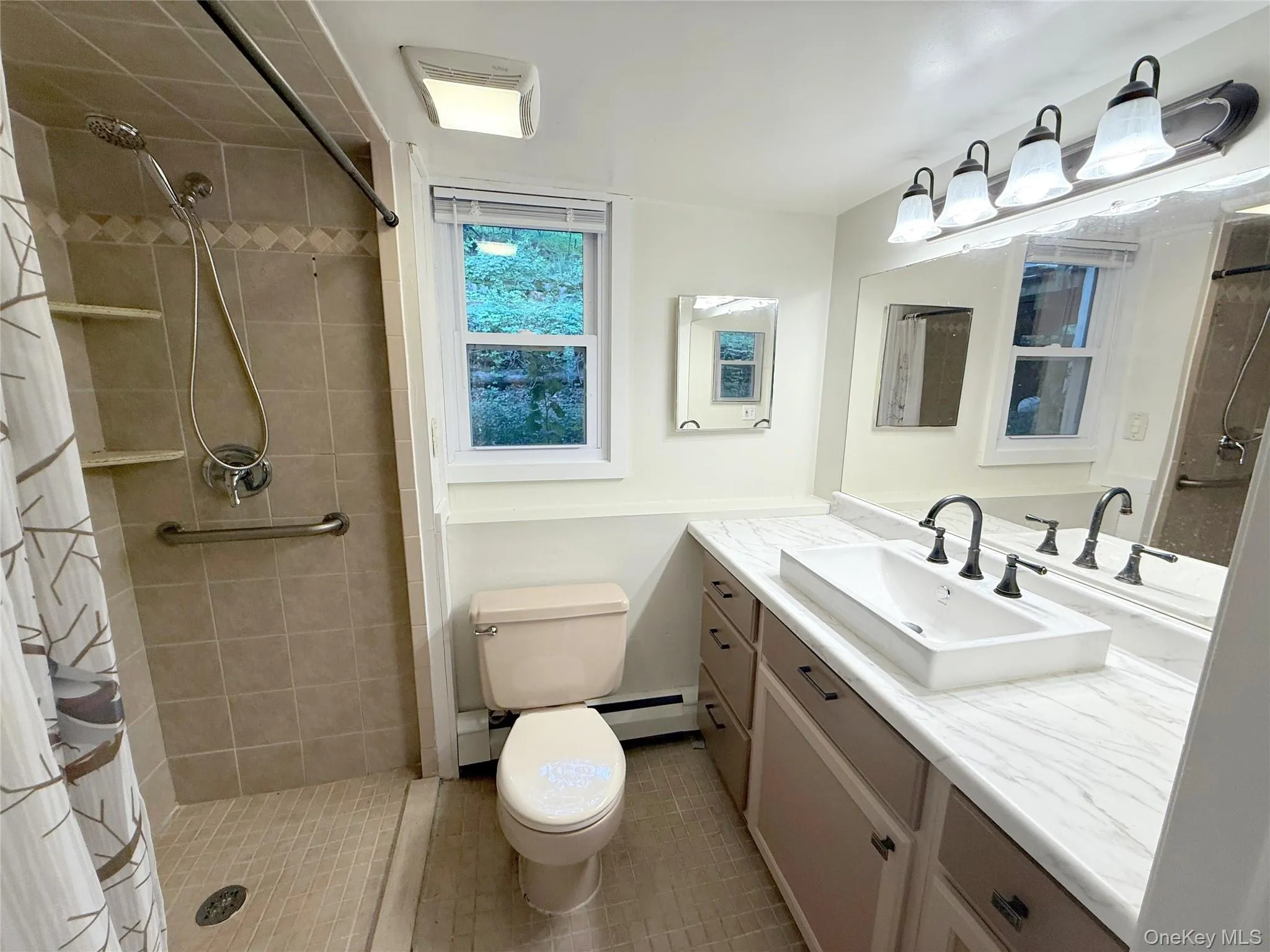 Full bathroom with vanity, tiled shower, light tile patterned flooring, and a baseboard radiator Full bathroom with vanity, tiled shower, light tile patterned flooring, and a baseboard radiator