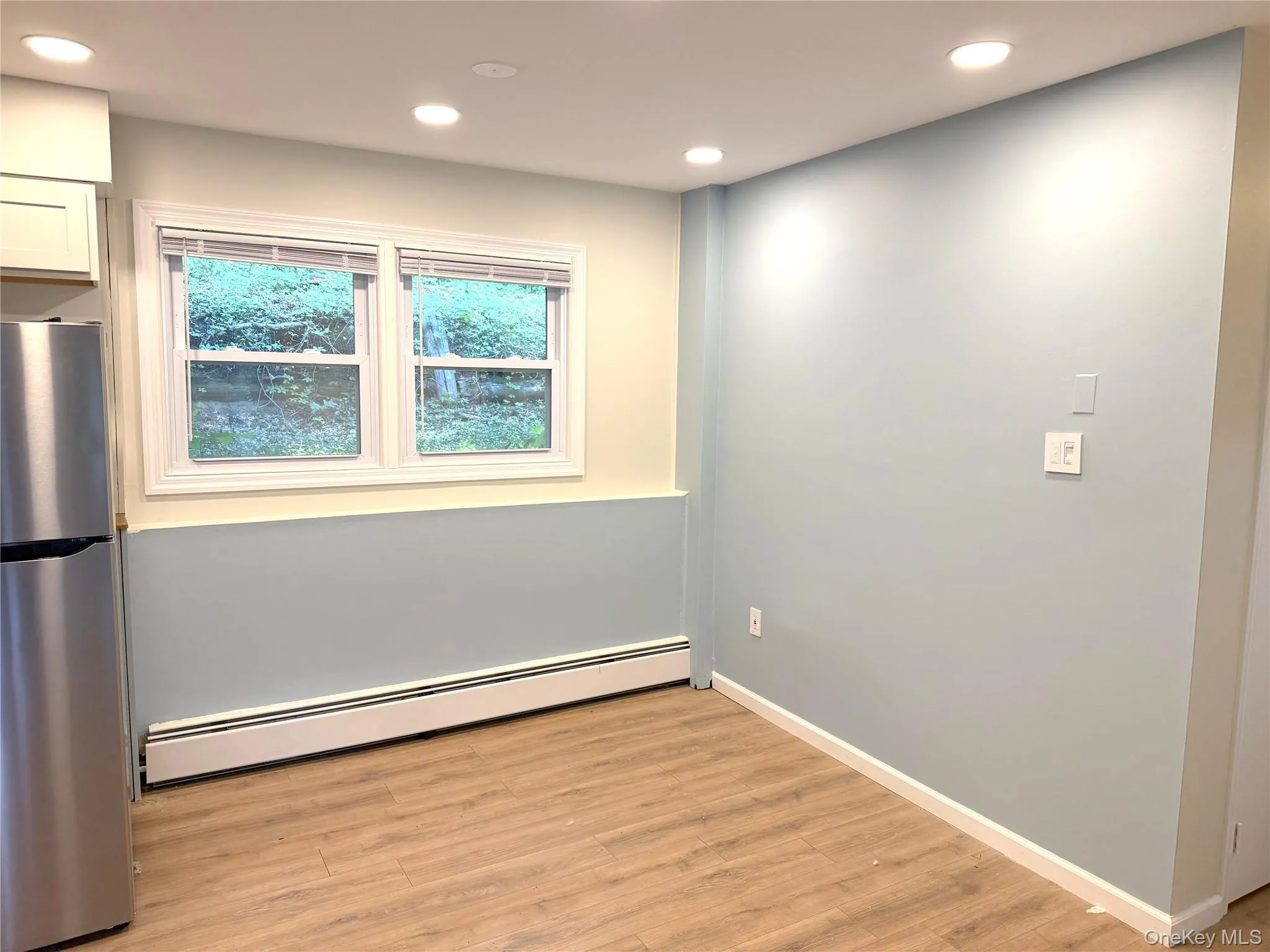 Unfurnished room with a baseboard radiator, recessed lighting, and light wood-type flooring Unfurnished room with a baseboard radiator, recessed lighting, and light wood-type flooring