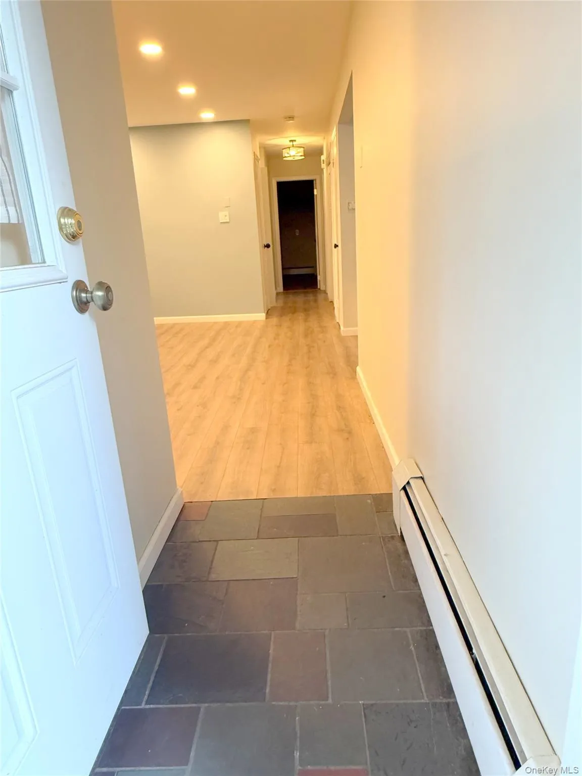 Corridor featuring a baseboard heating unit and baseboards Corridor featuring a baseboard heating unit and baseboards