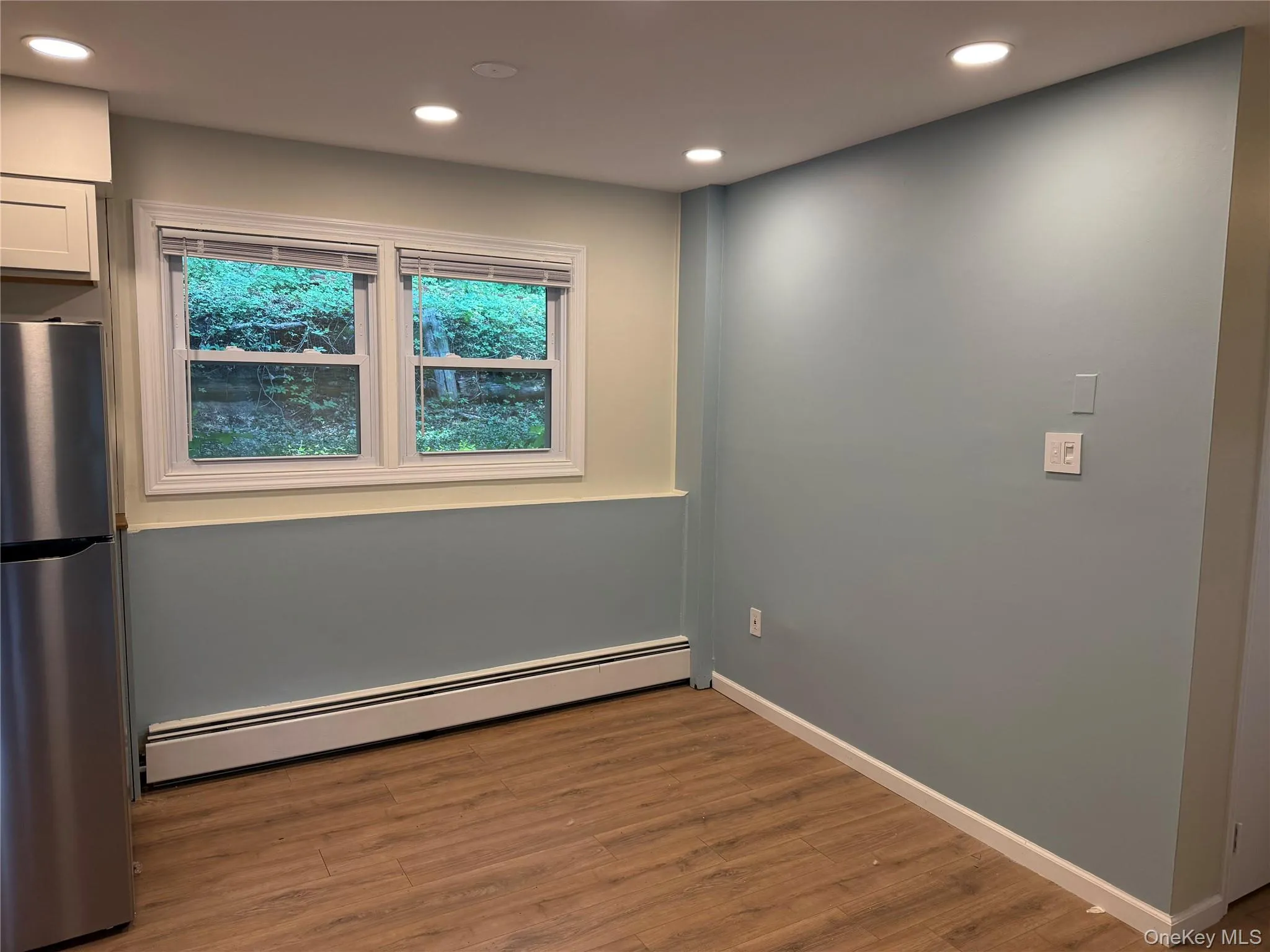 Unfurnished room with baseboard heating, recessed lighting, and wood finished floors Unfurnished room with baseboard heating, recessed lighting, and wood finished floors