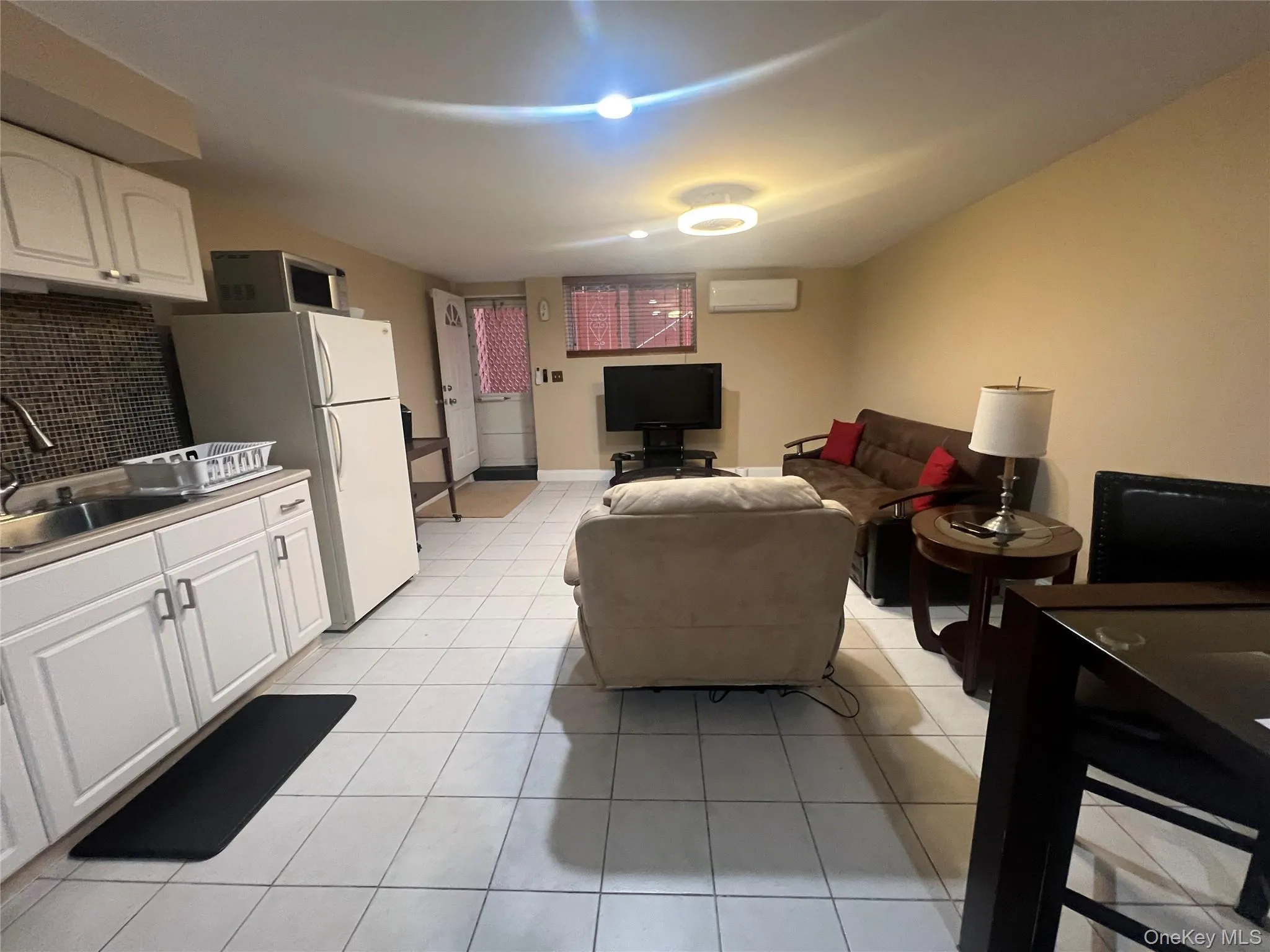 Living room with light tile patterned floors and a wall unit AC Living room with light tile patterned floors and a wall unit AC