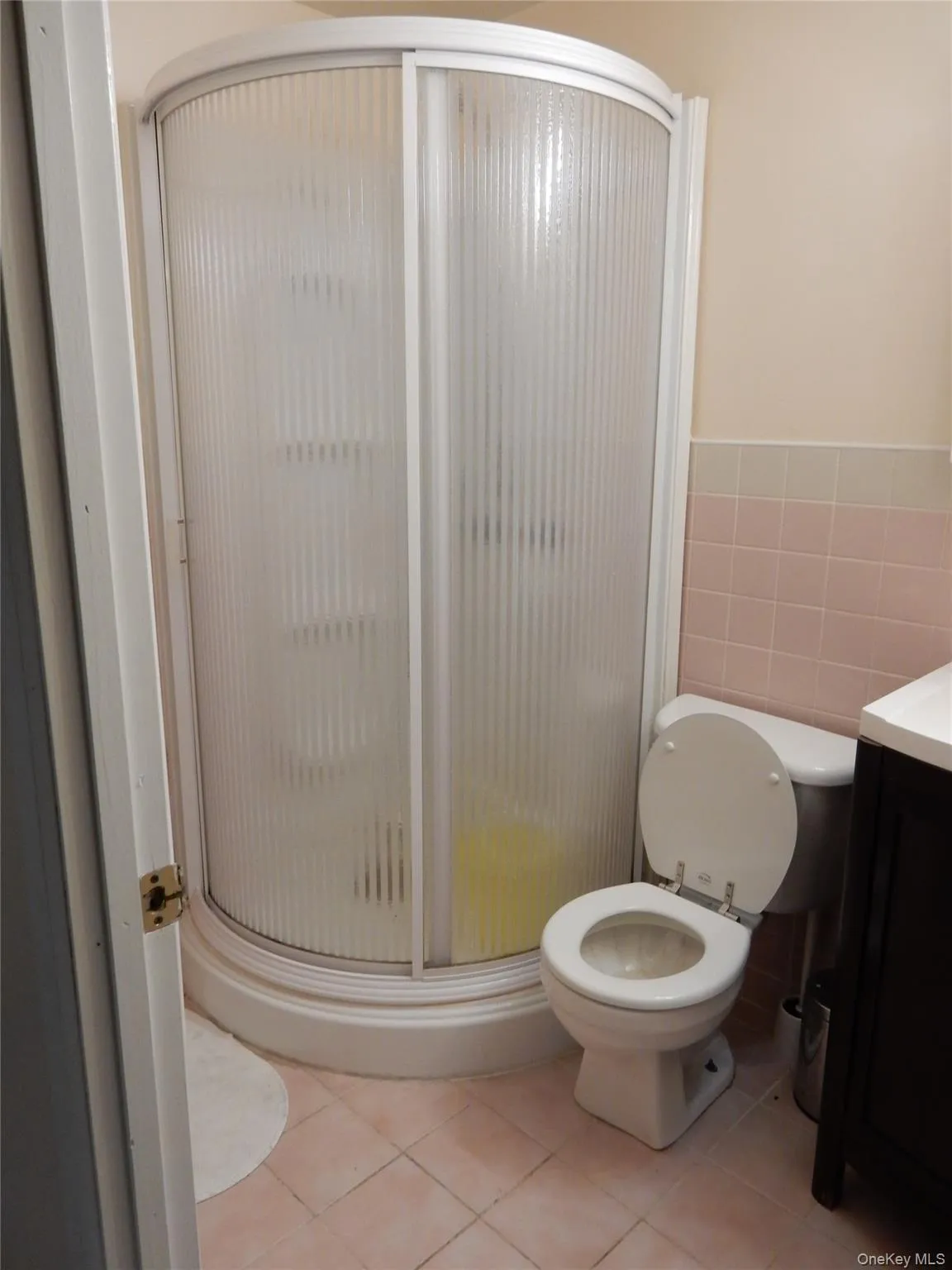 Bathroom featuring a shower stall, light tile patterned floors, vanity, and tile walls Bathroom featuring a shower stall, light tile patterned floors, vanity, and tile walls