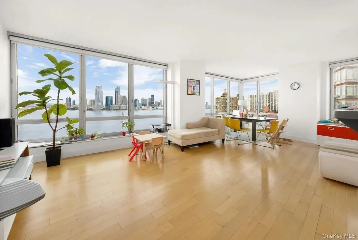 Living area featuring a skyline view, light wood-type flooring, and a wall of windows Living area featuring a skyline view, light wood-type flooring, and a wall of windows