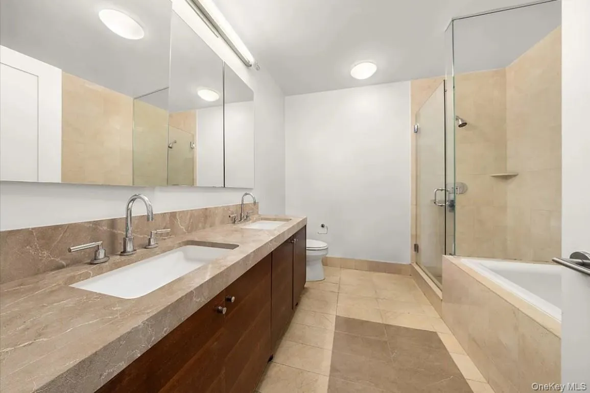 Bathroom with a shower stall, double vanity, a garden tub, and light tile patterned flooring Bathroom with a shower stall, double vanity, a garden tub, and light tile patterned flooring
