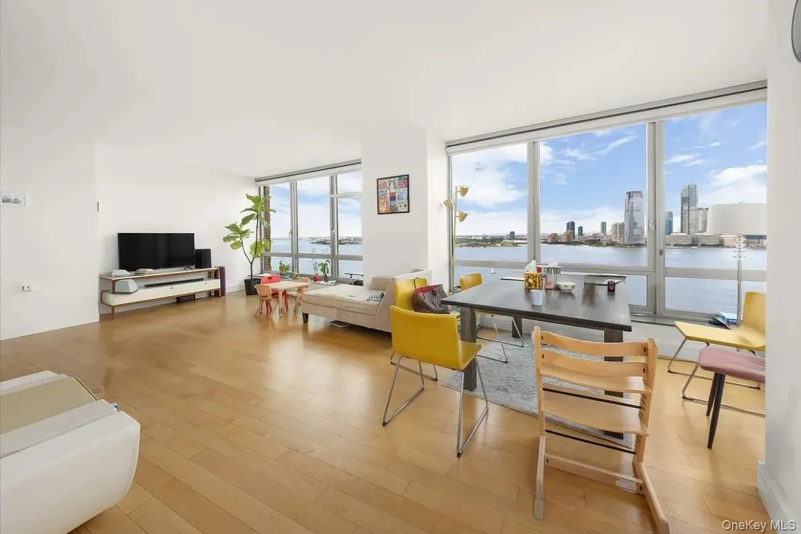 Living room with floor to ceiling windows, light wood-type flooring, and a view of skyline Living room with floor to ceiling windows, light wood-type flooring, and a view of skyline