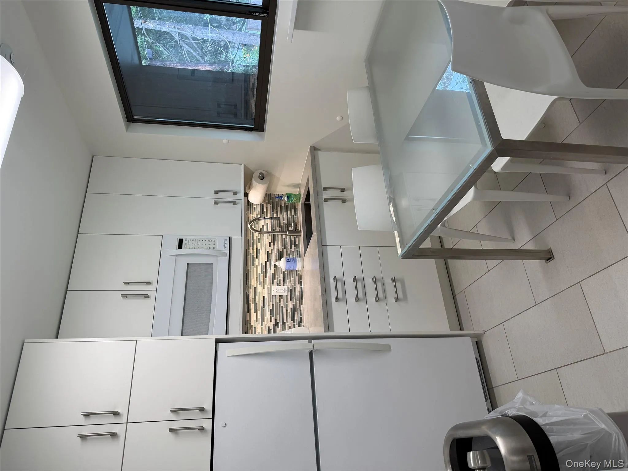 Kitchen featuring white fridge, white cabinets, tasteful backsplash, and light tile patterned floors Kitchen featuring white fridge, white cabinets, tasteful backsplash, and light tile patterned floors
