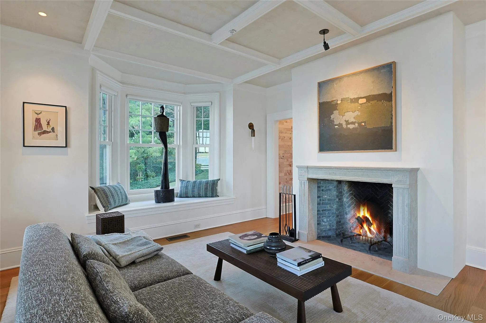 Living area featuring beam ceiling, a high end fireplace, coffered ceiling, and wood finished floors Living area featuring beam ceiling, a high end fireplace, coffered ceiling, and wood finished floors