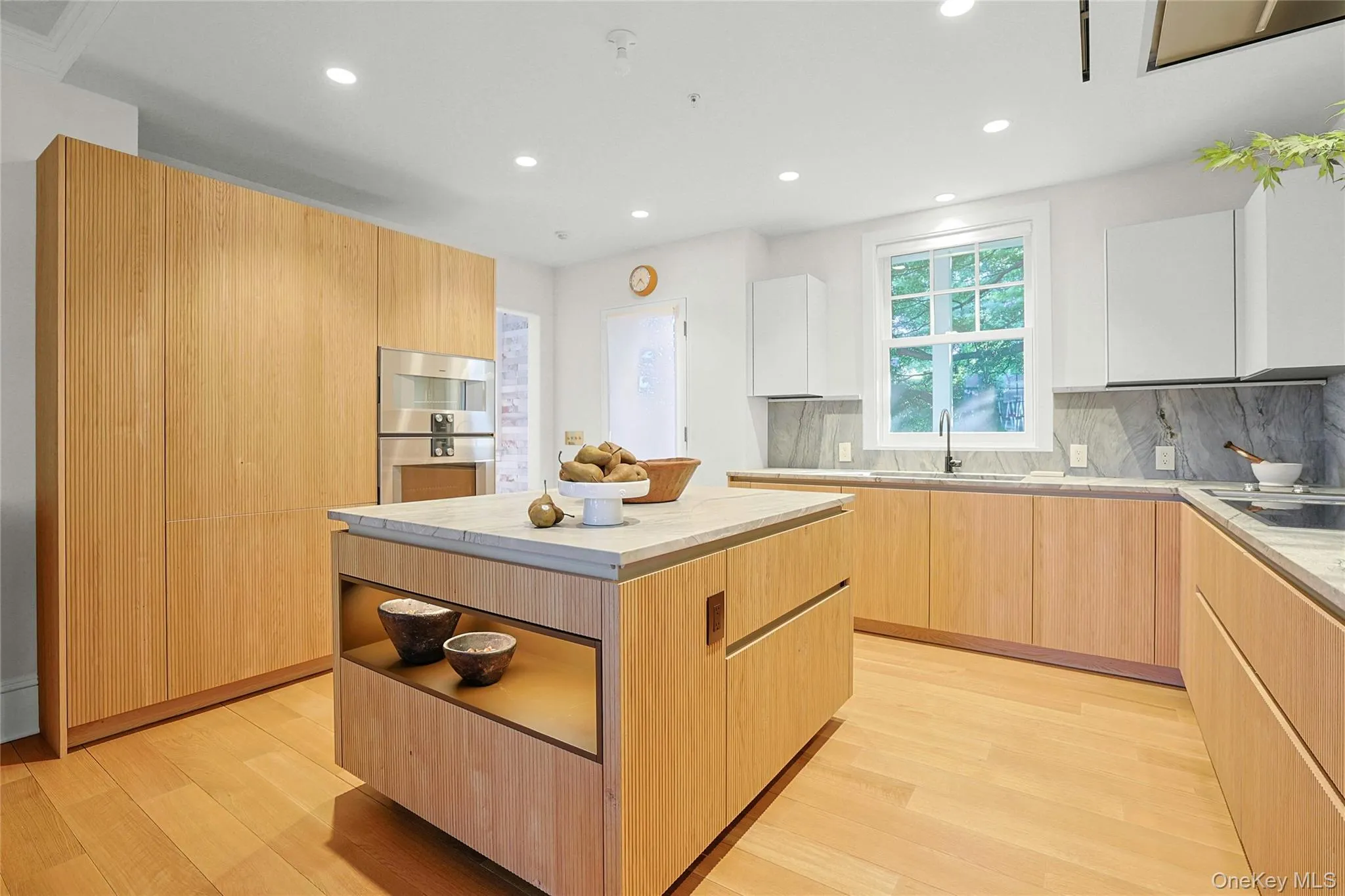 Kitchen with light brown cabinetry, a center island, modern cabinets, recessed lighting, and light countertops Kitchen with light brown cabinetry, a center island, modern cabinets, recessed lighting, and light countertops