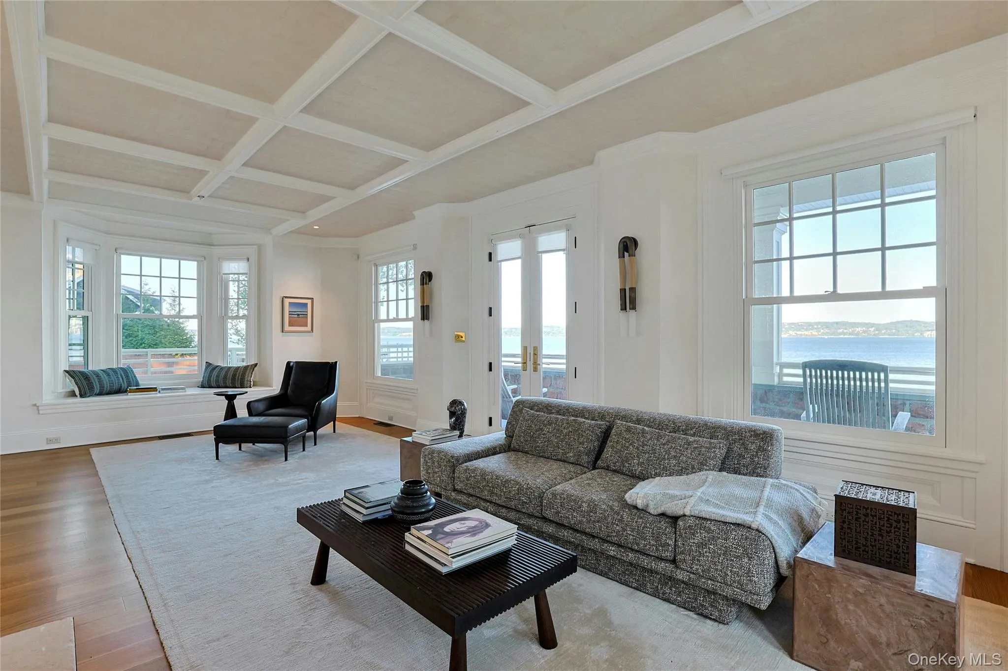 Living area with coffered ceiling, a water view, wood finished floors, beamed ceiling, and french doors Living area with coffered ceiling, a water view, wood finished floors, beamed ceiling, and french doors