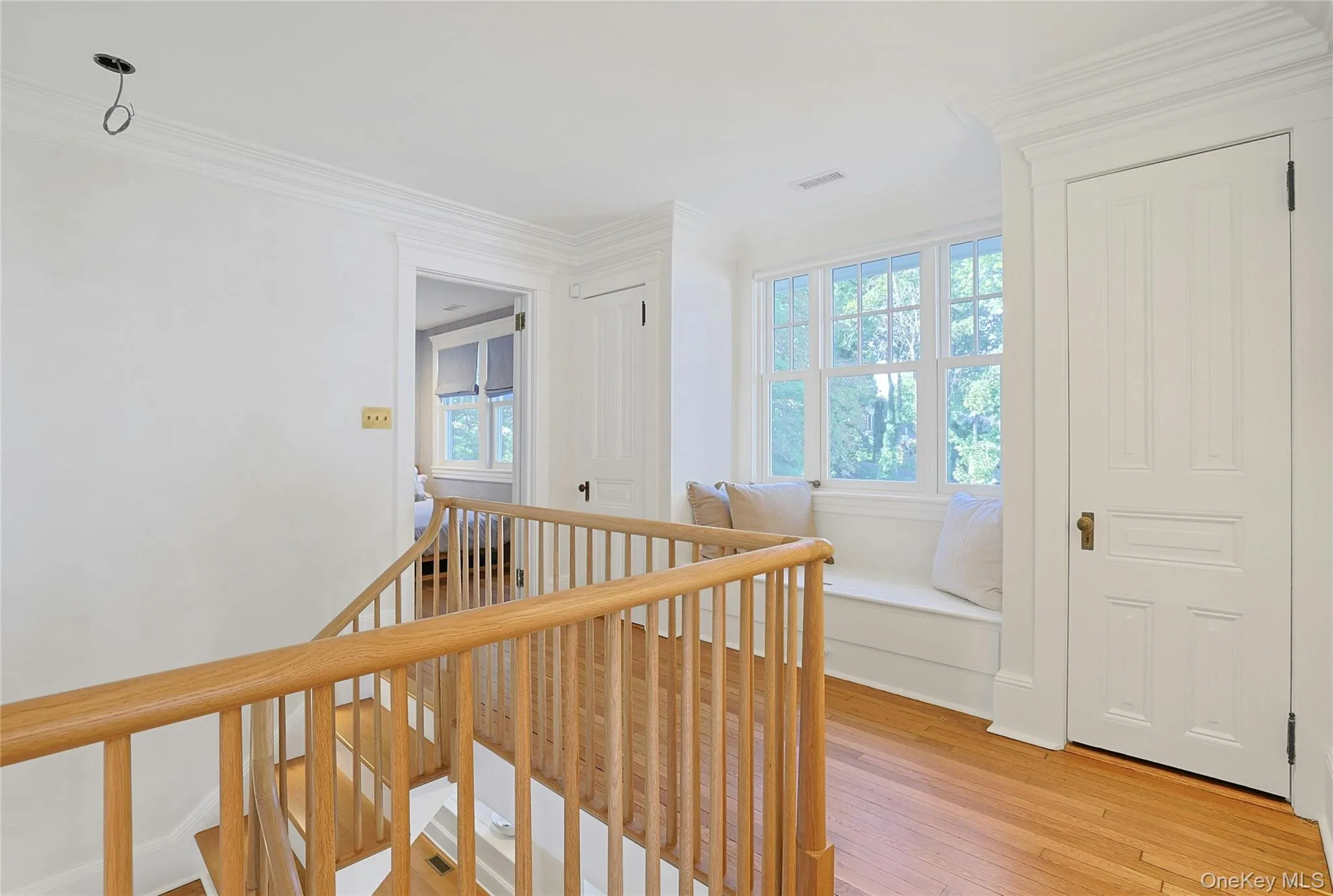 Hall with an upstairs landing, healthy amount of natural light, light wood-type flooring, and crown molding Hall with an upstairs landing, healthy amount of natural light, light wood-type flooring, and crown molding