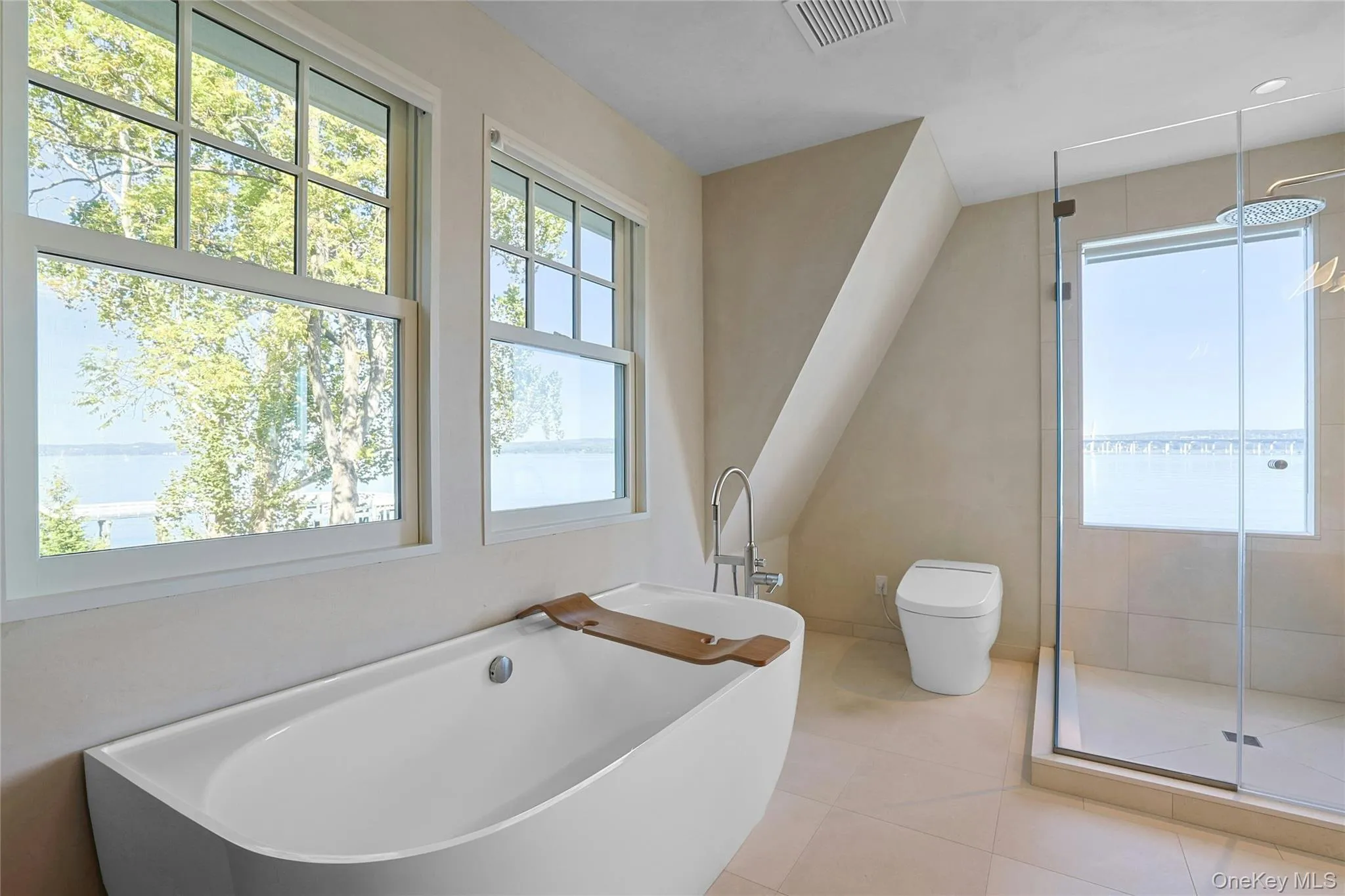 Full bath featuring a freestanding bath, a stall shower, light tile patterned flooring, and healthy amount of natural light Full bath featuring a freestanding bath, a stall shower, light tile patterned flooring, and healthy amount of natural light